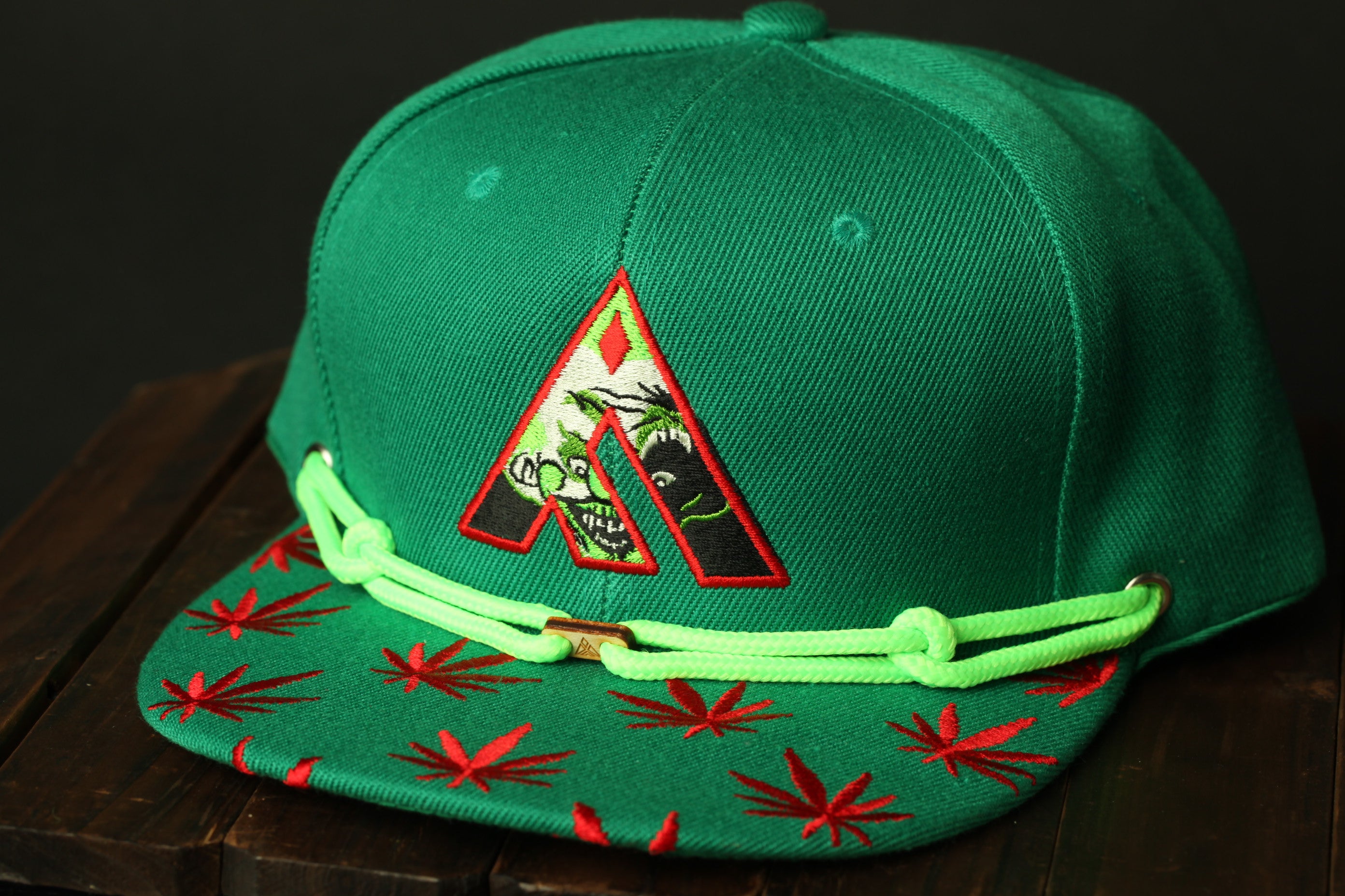 A green baseball cap with a red and green leaf pattern and a red and green leaf pattern on the brim.