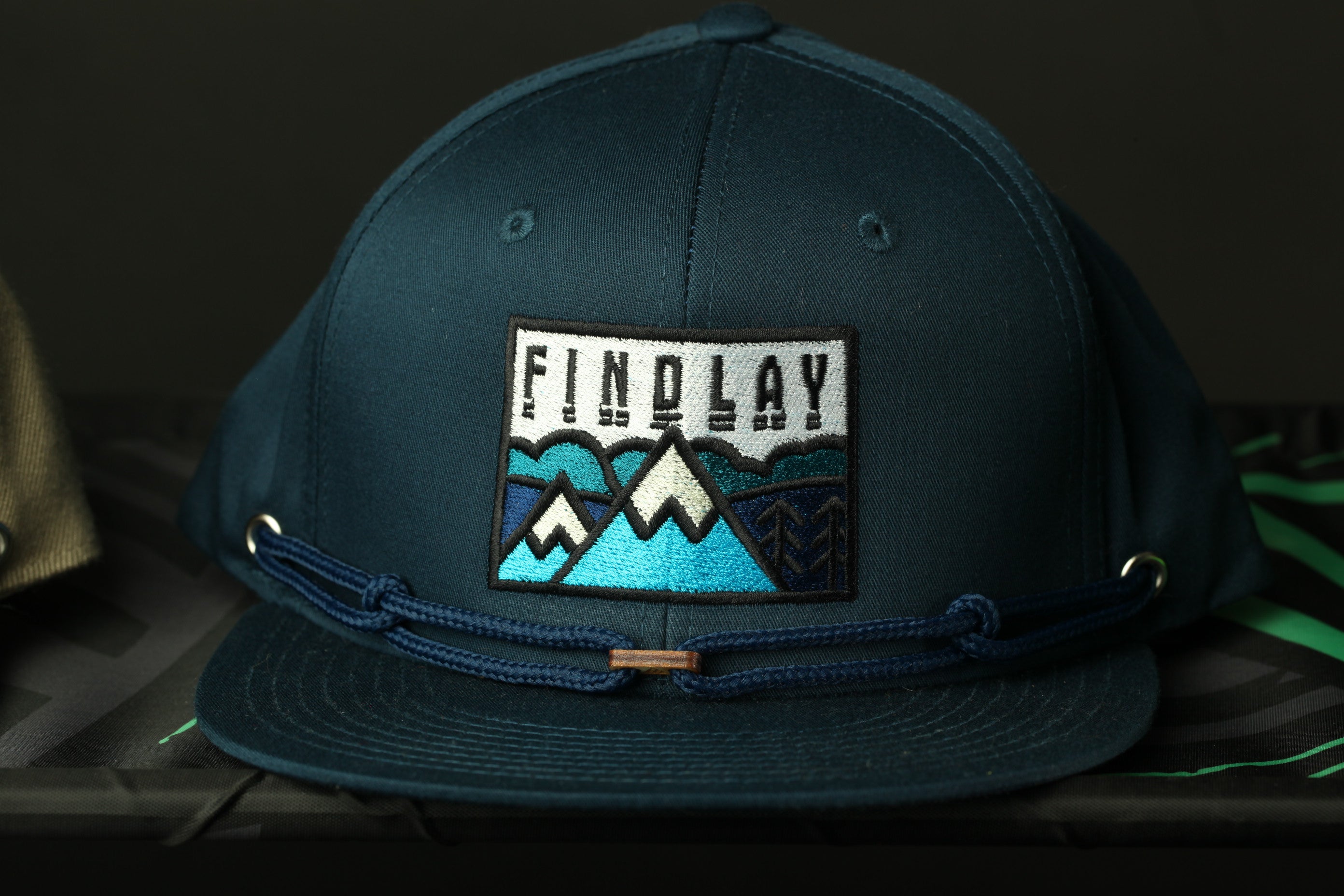 A dark blue baseball cap with a patch on the front displaying the word "FINDlay".