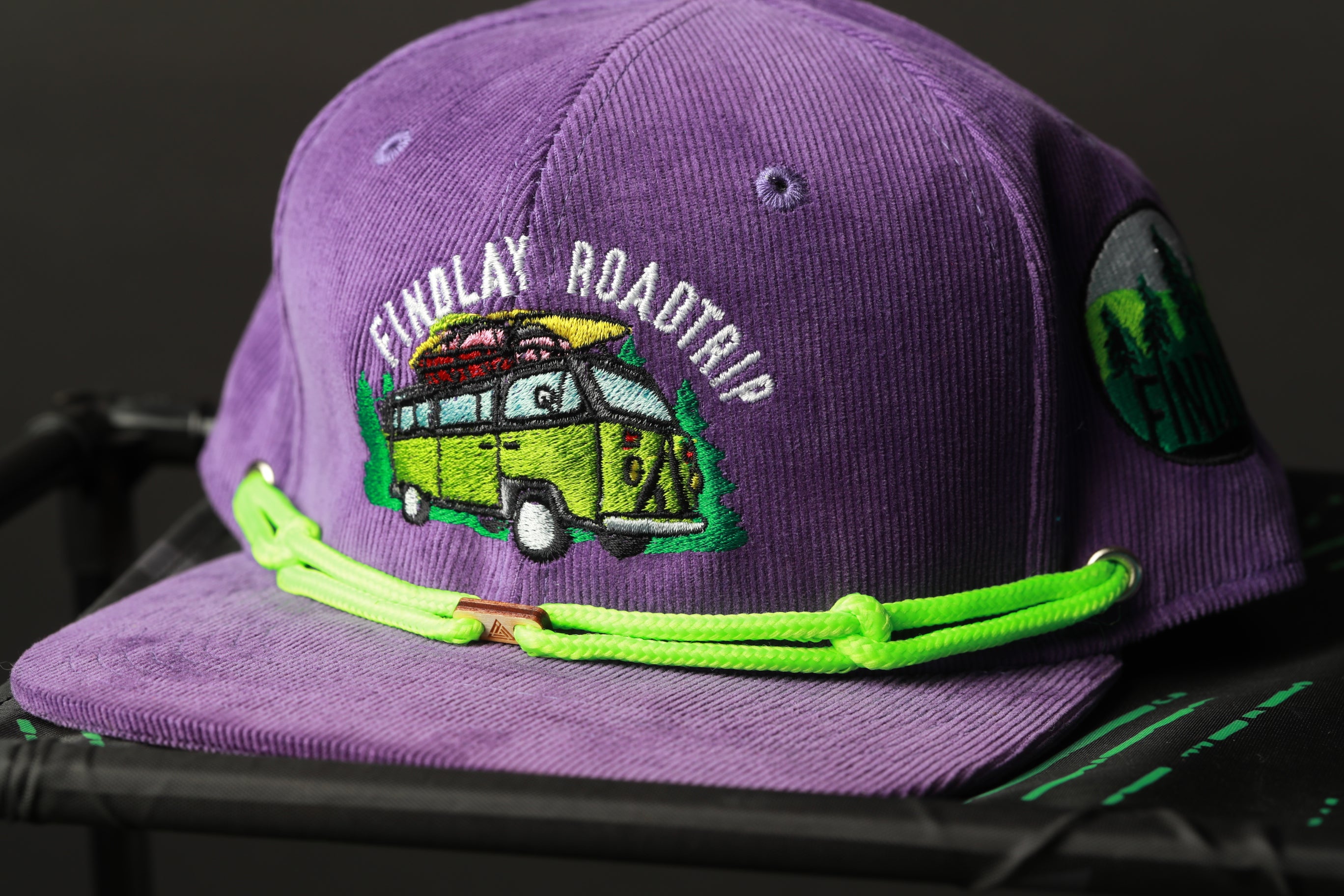 A purple baseball cap with a green strap and a graphic of a van on it.