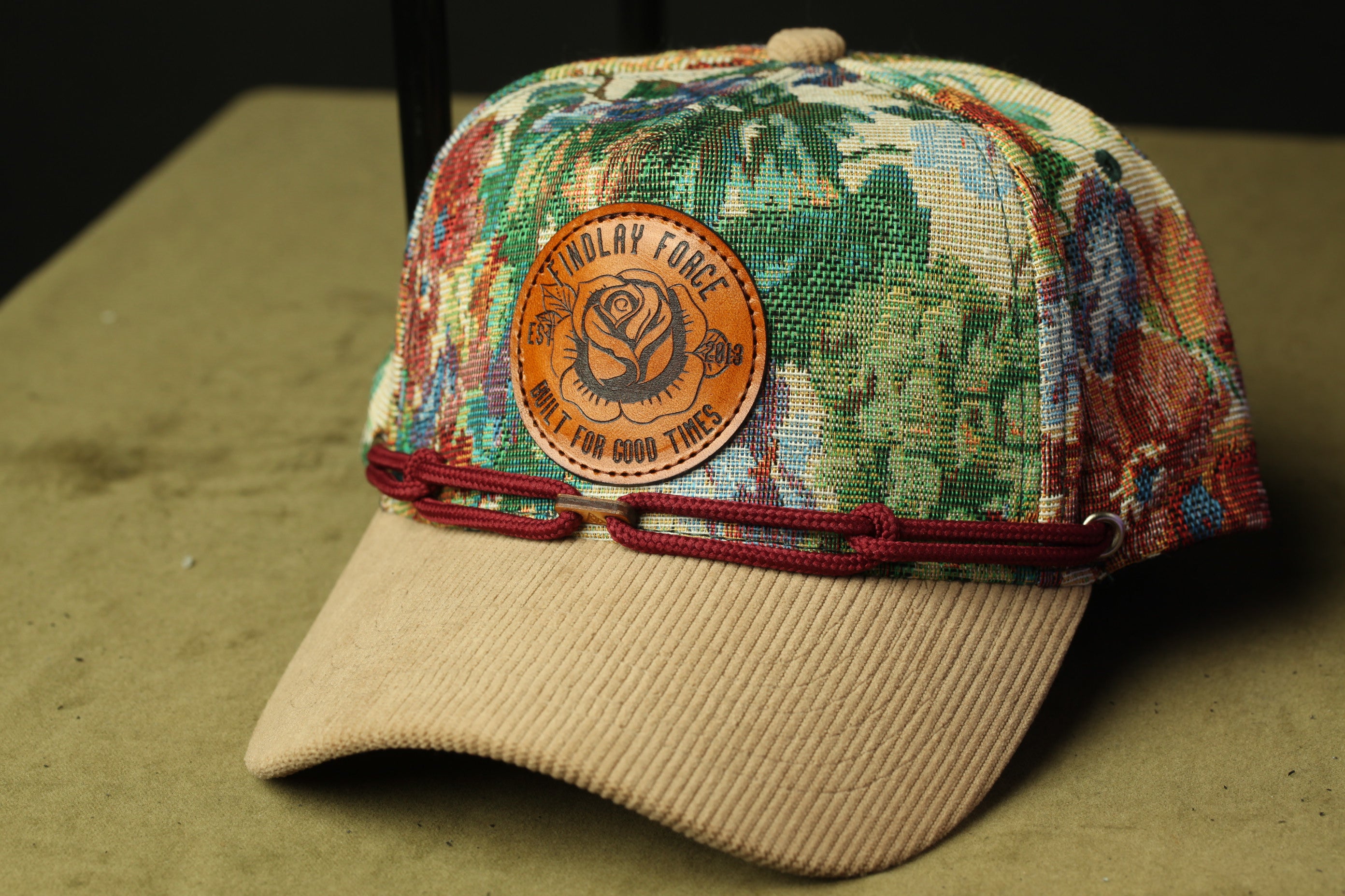 A colorful, patterned baseball cap with a leather patch on the front.