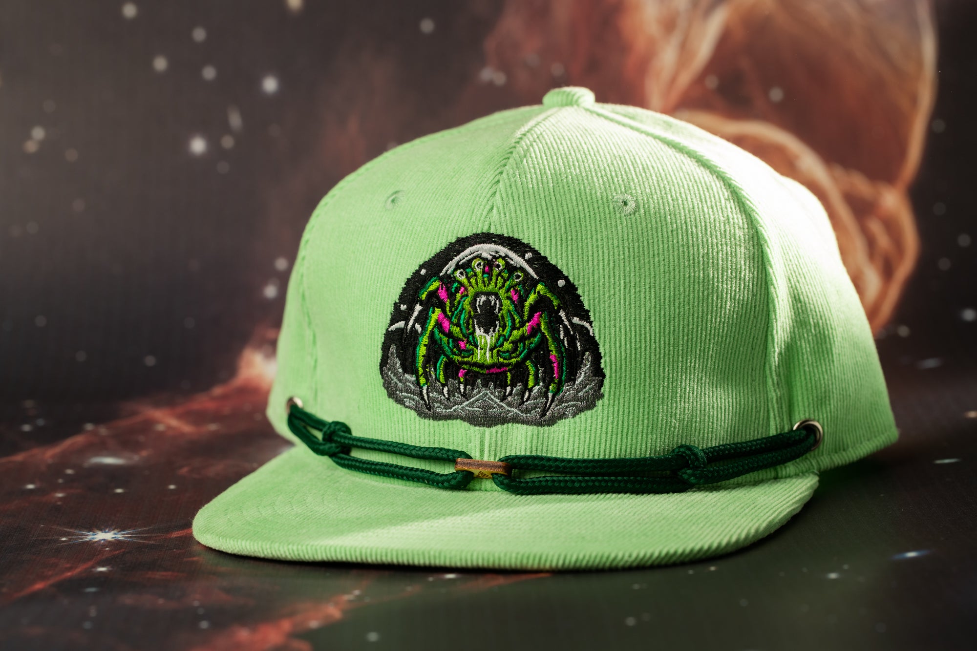 A green baseball cap with a unique embroidered design on the front.