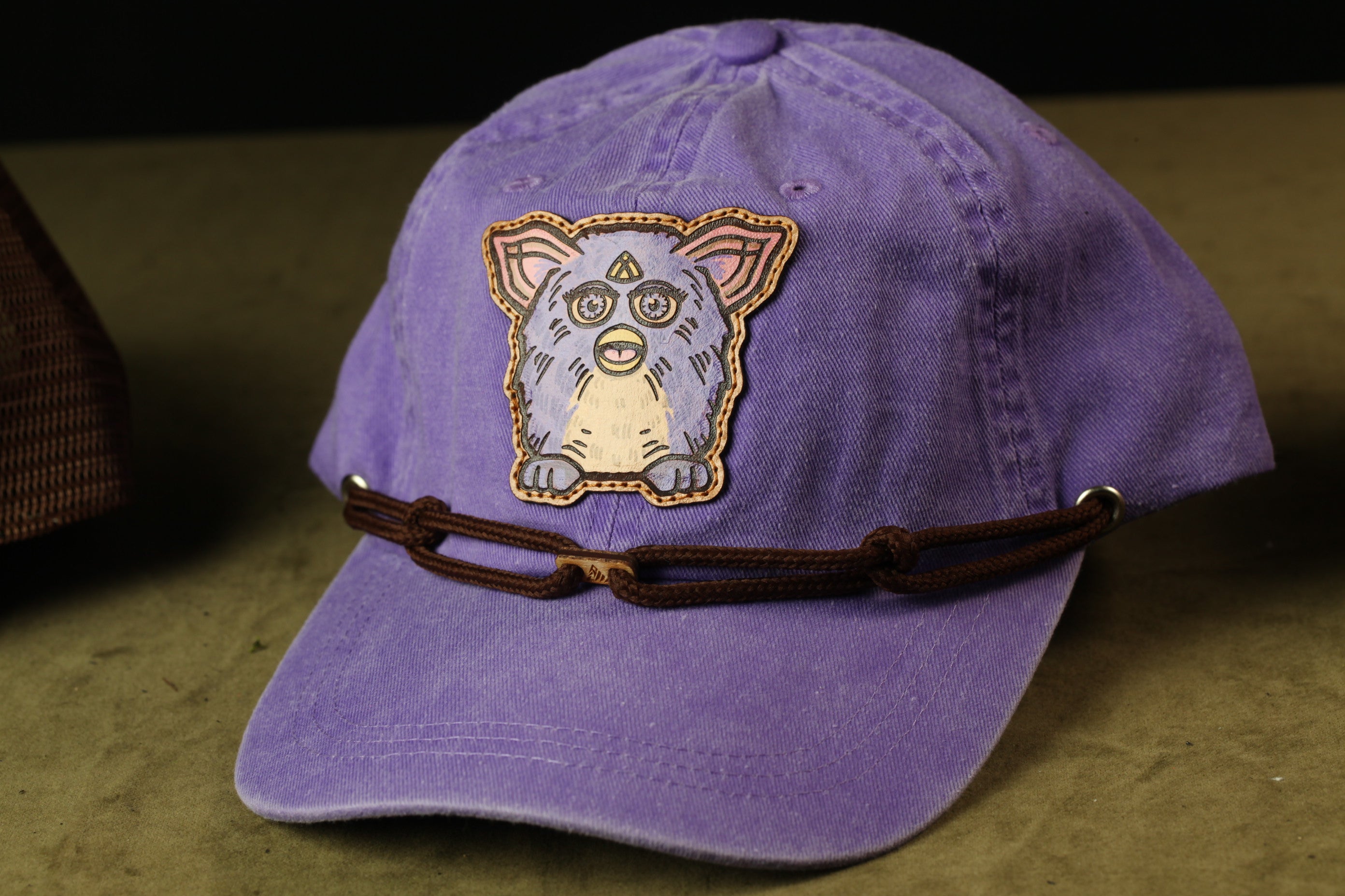 A purple baseball cap with a cartoon character design on the front.