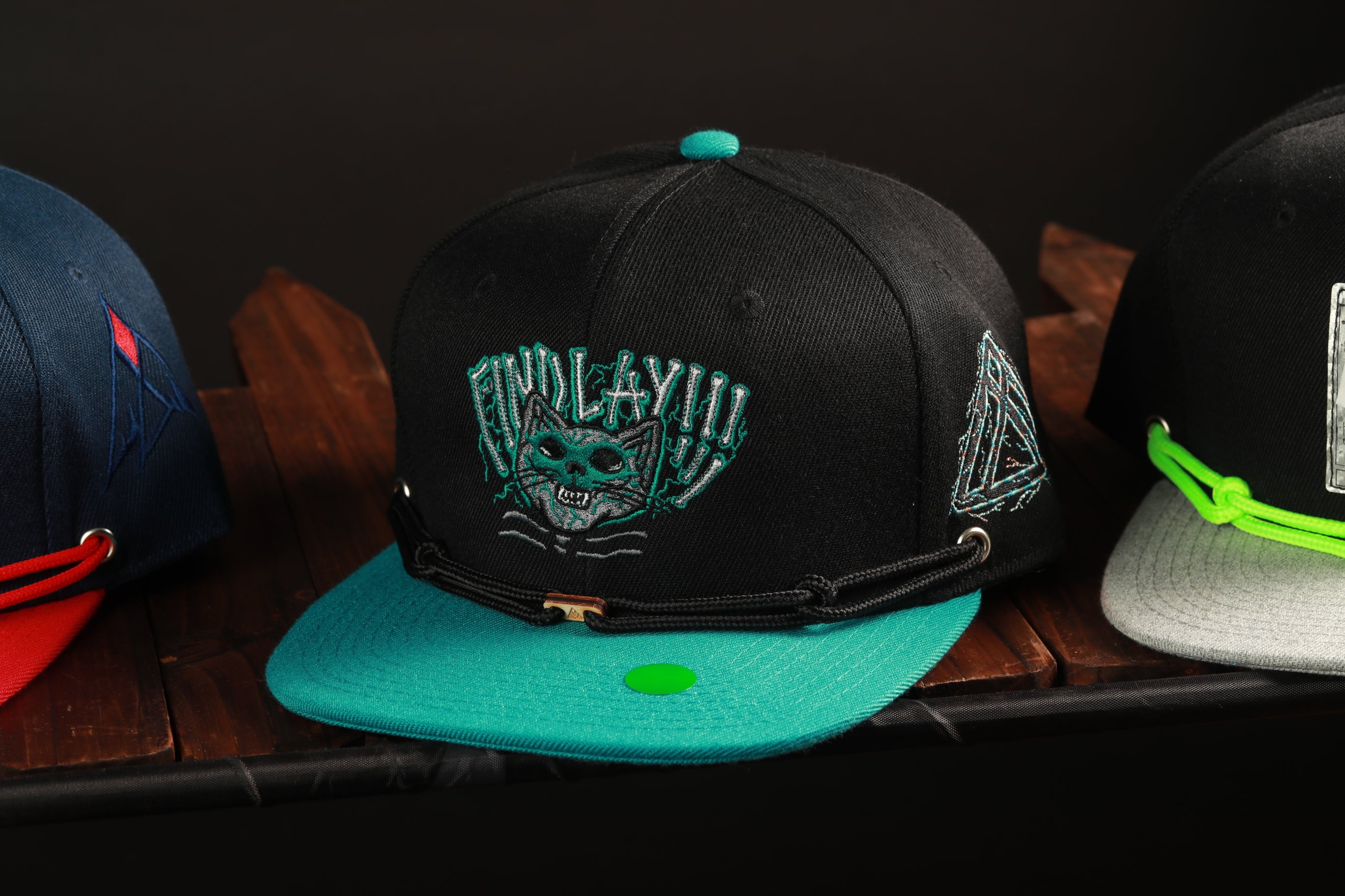 A collection of colorful baseball caps on a wooden surface, with one prominently displaying a skull and crossbones design.