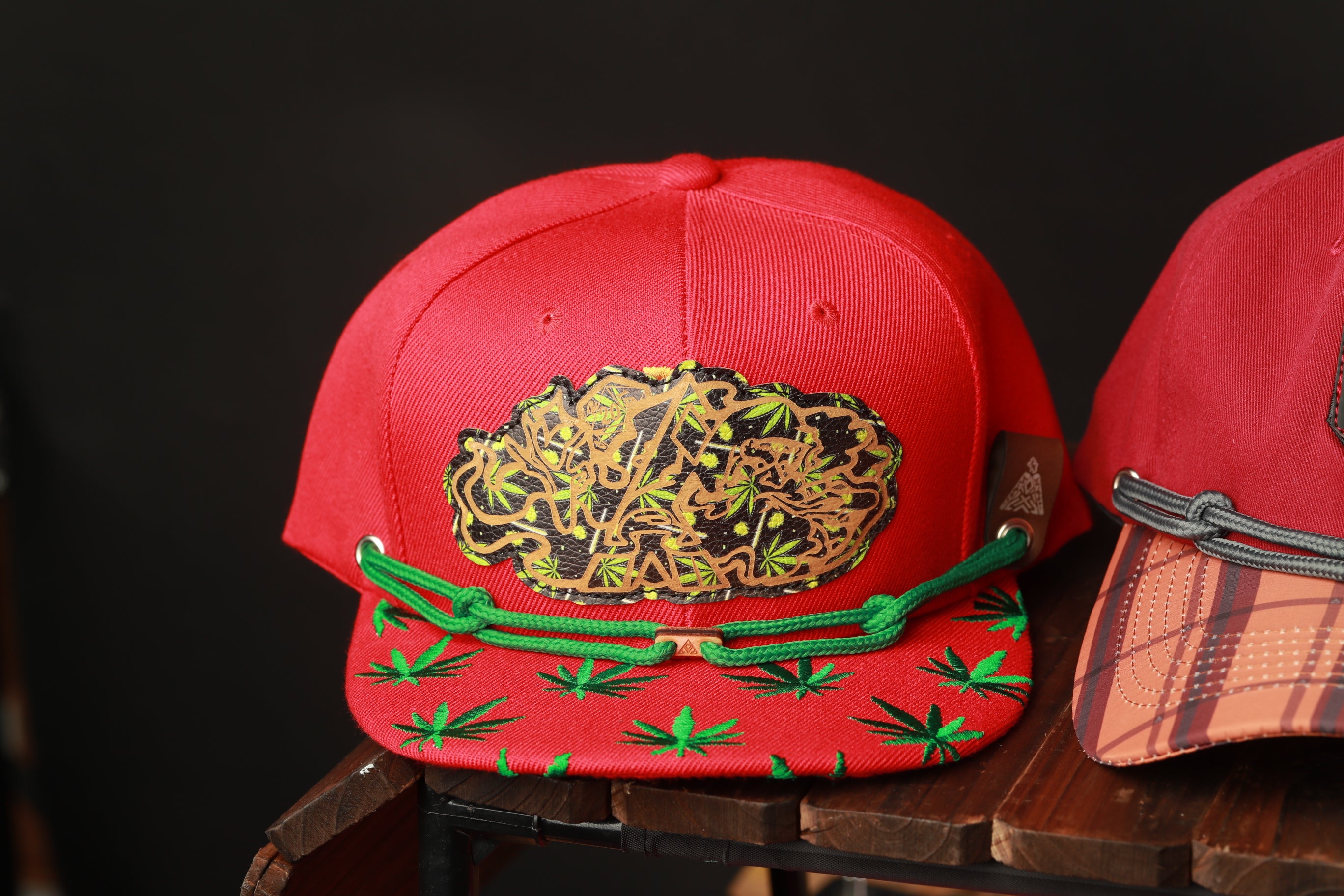 a red baseball cap with a unique design featuring green leaves and a brown background.