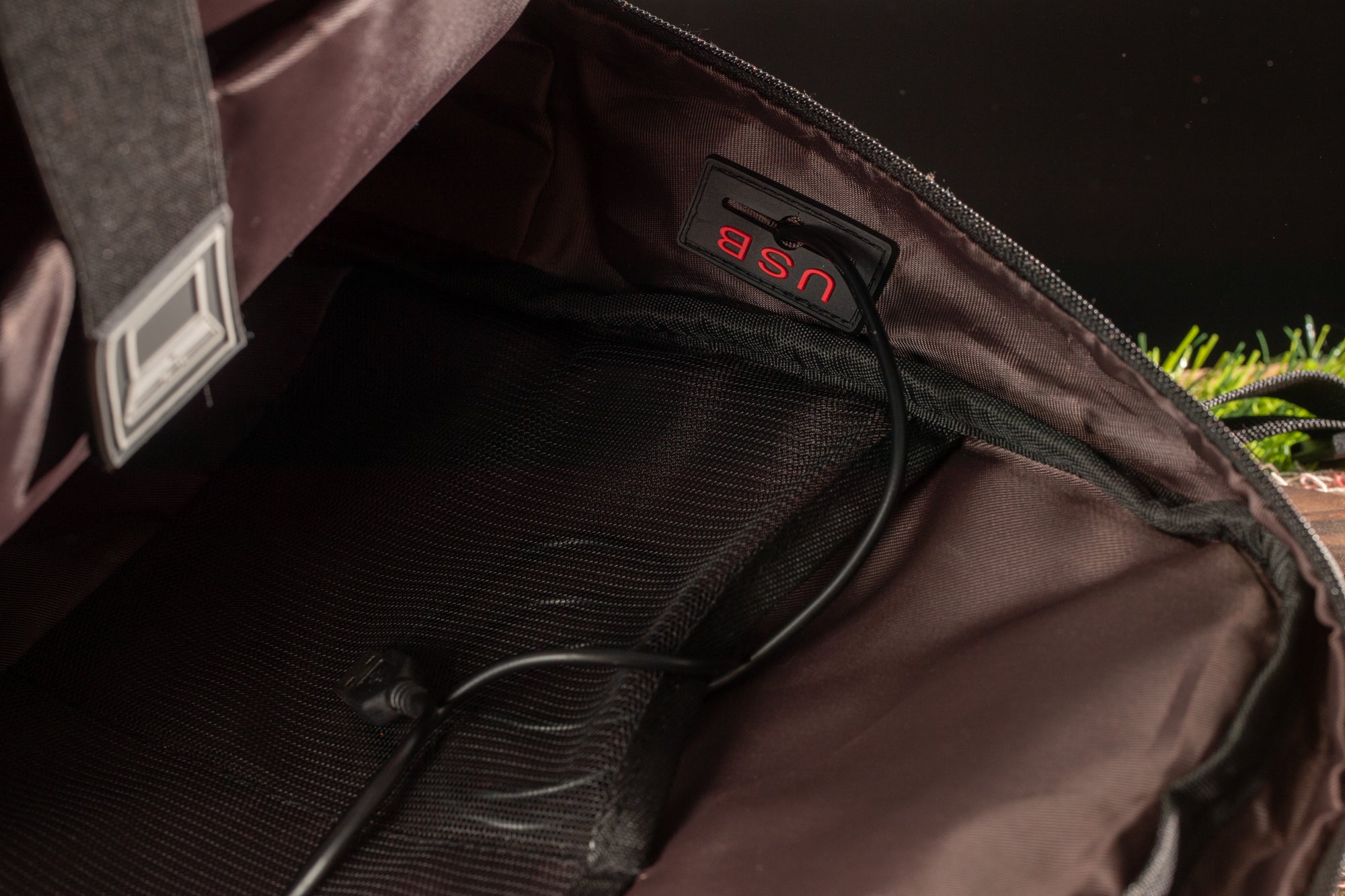 the interior of a bag, with a USB cable plugged into the side pocket.