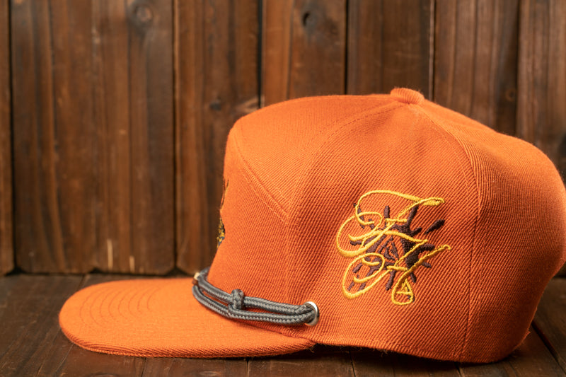 An orange baseball cap with a gray strap is placed on a wooden surface.