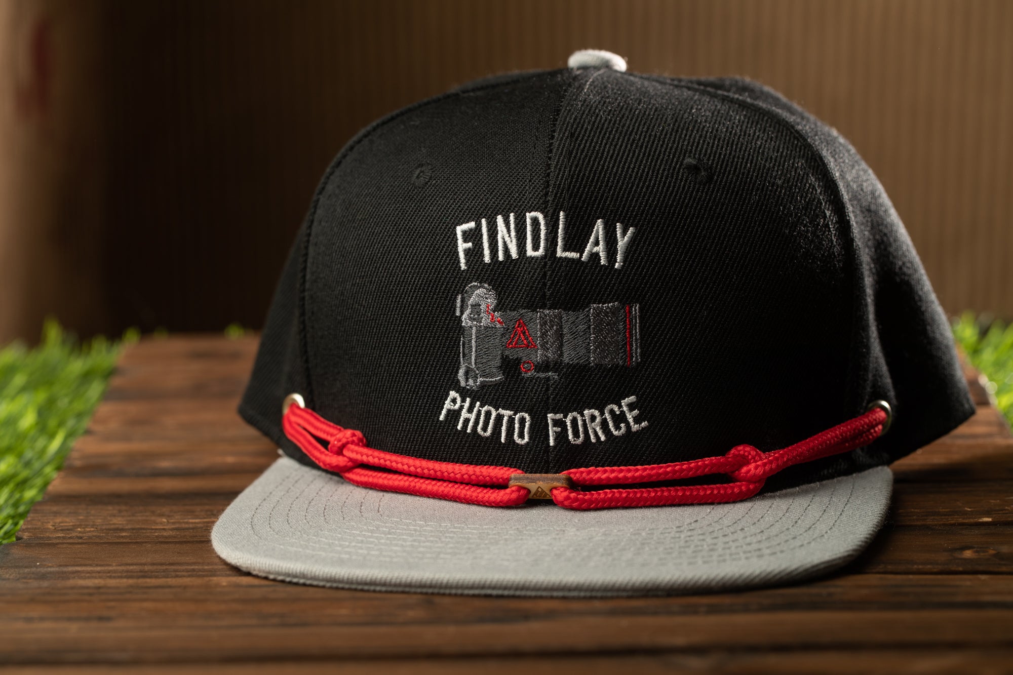 A black baseball cap with a red string and the text "FIND LAY PHOTO FORCE" printed on it.