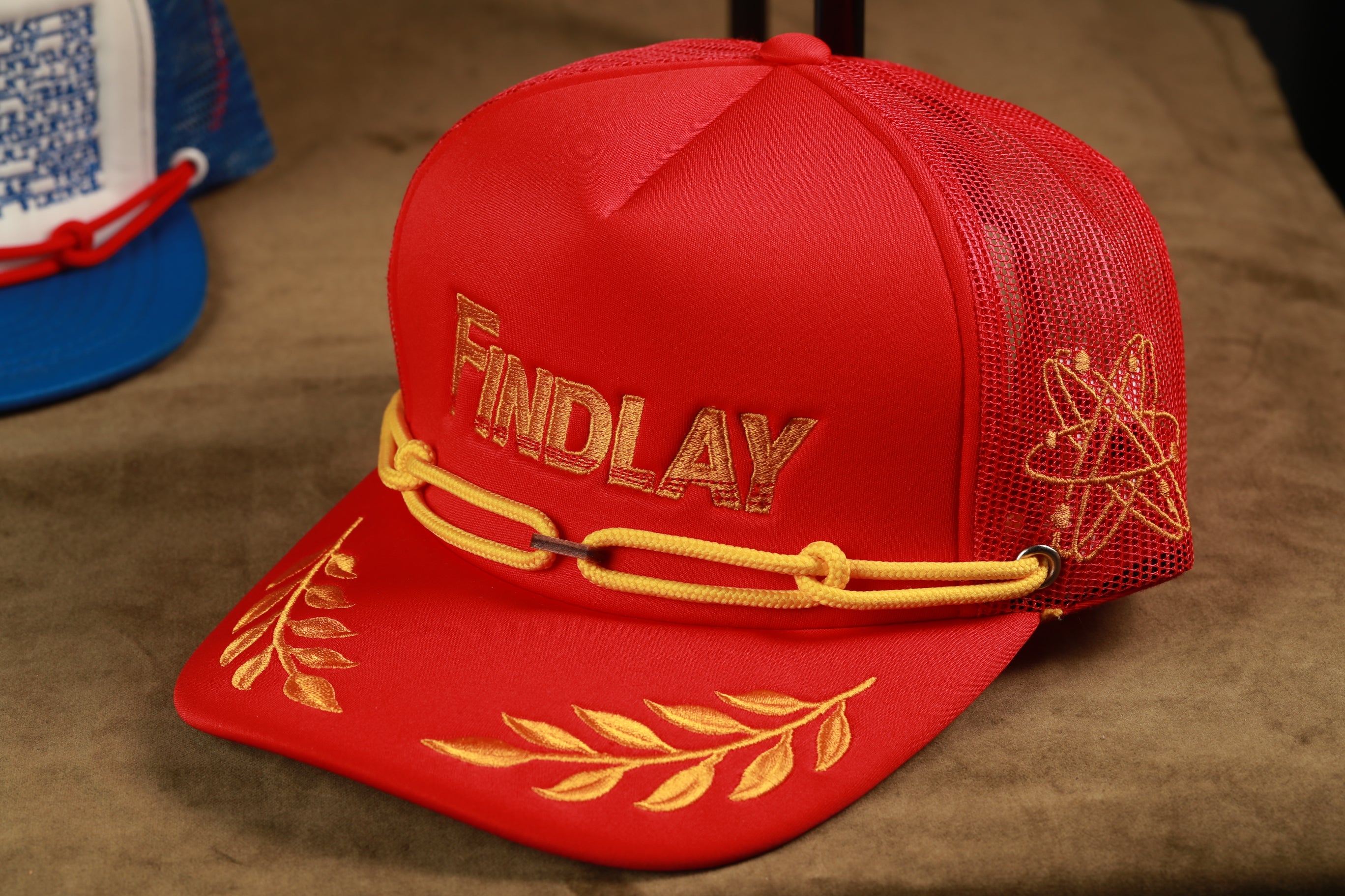 A red baseball cap with the word "FINDlay" printed on it, sitting on a brown surface.
