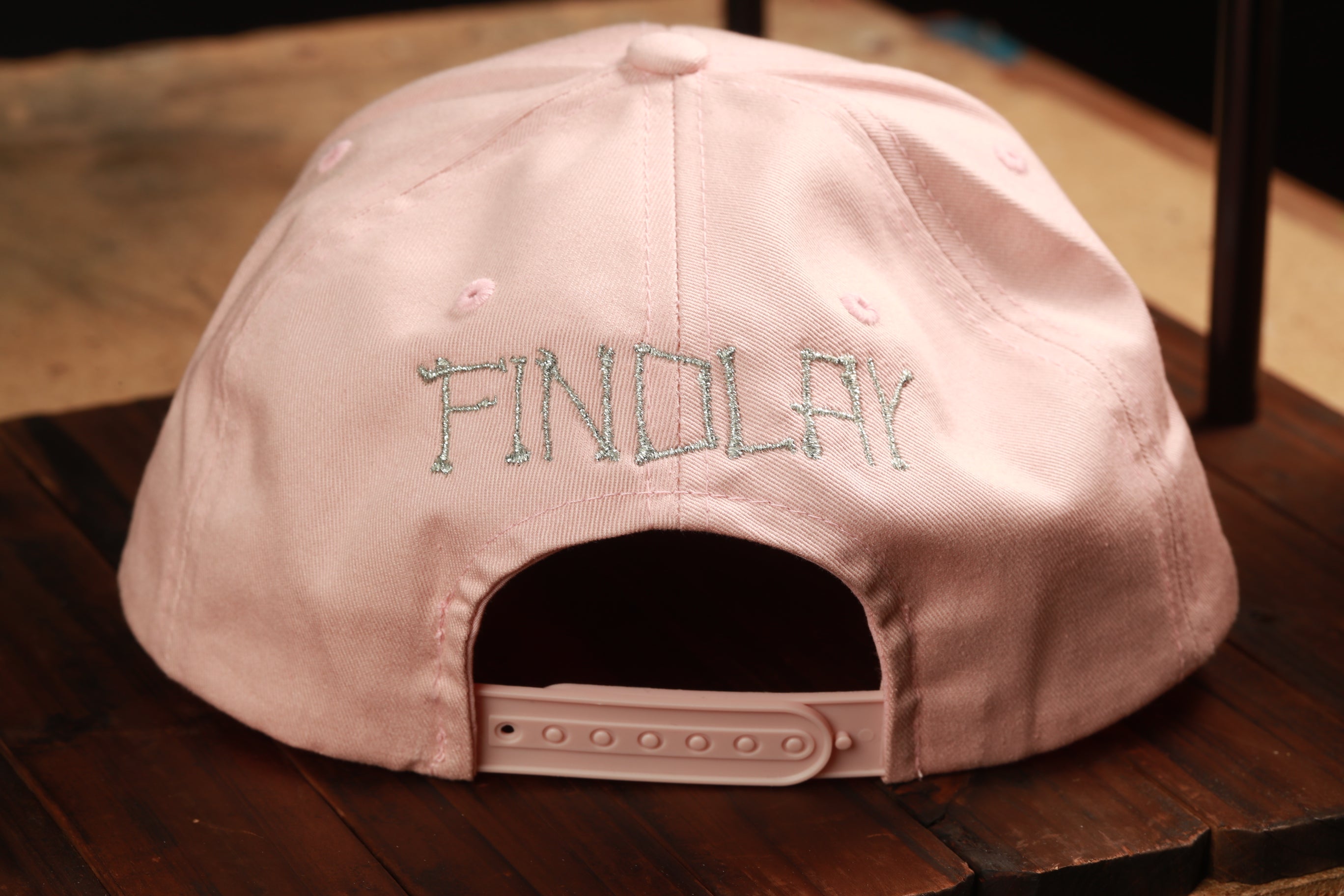 A pink baseball cap with the word "FINDlay" embroidered on it.