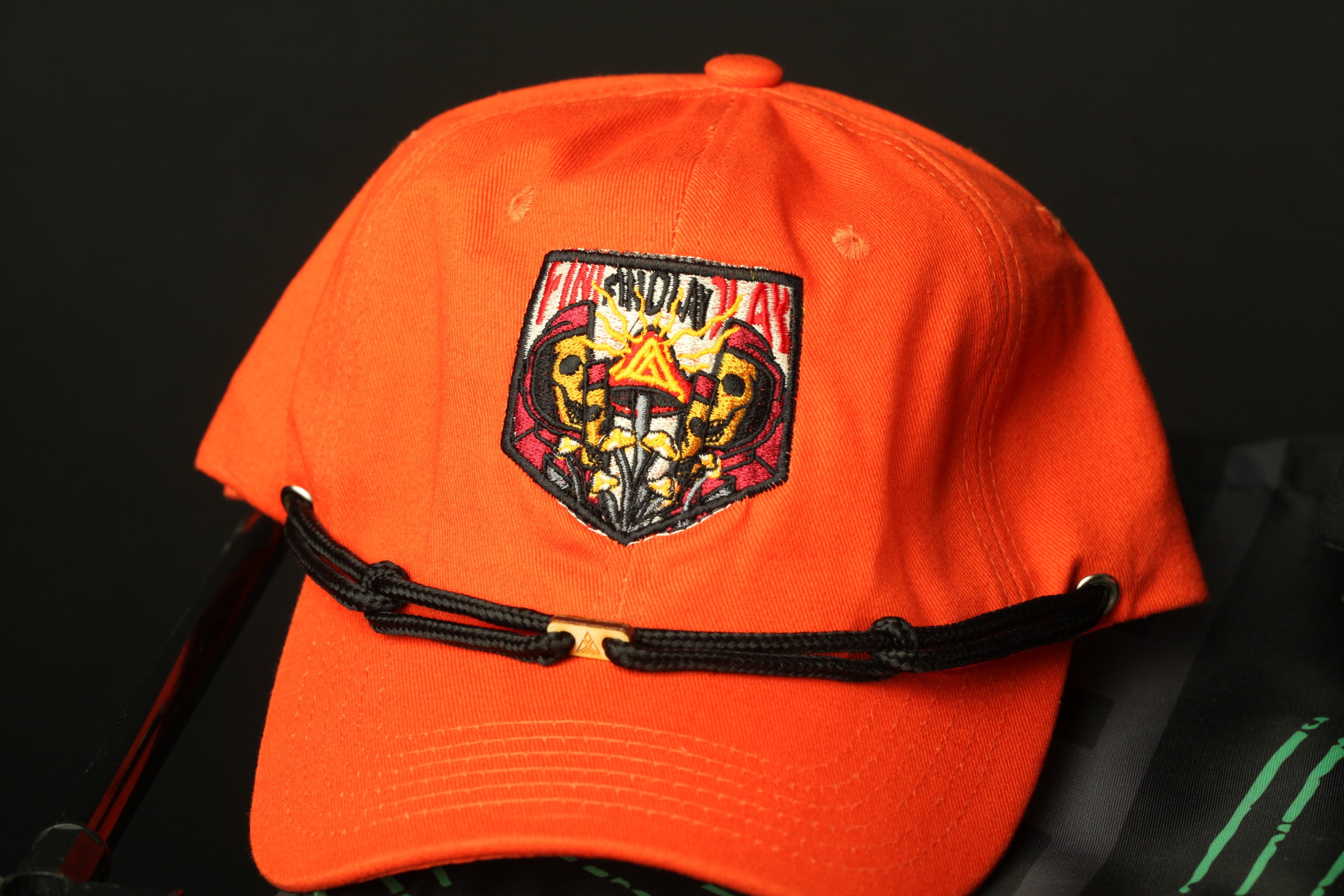 An orange baseball cap with a black strap and a colorful patch on the front.