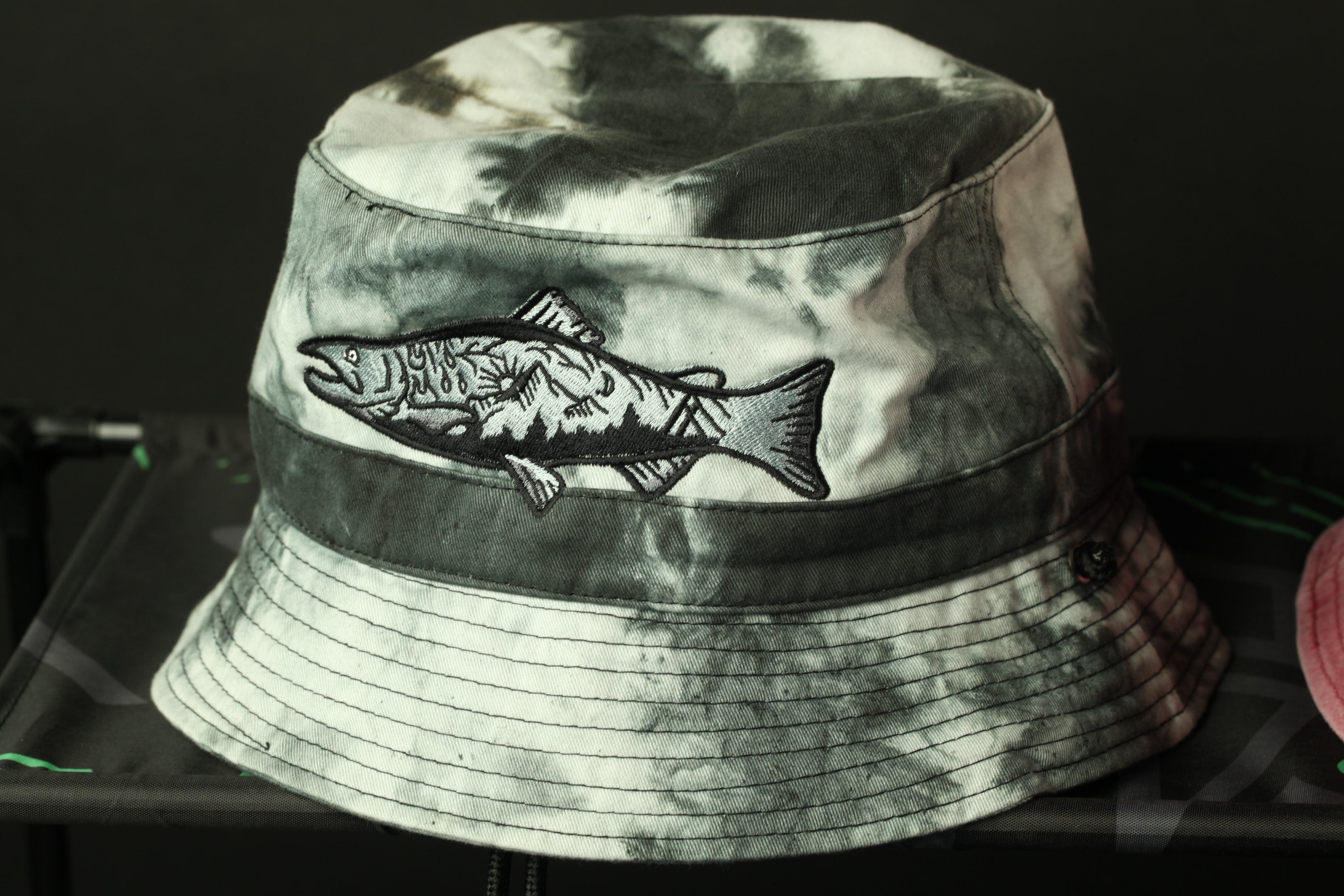 A black and white bucket hat with a fish embroidered on the front.