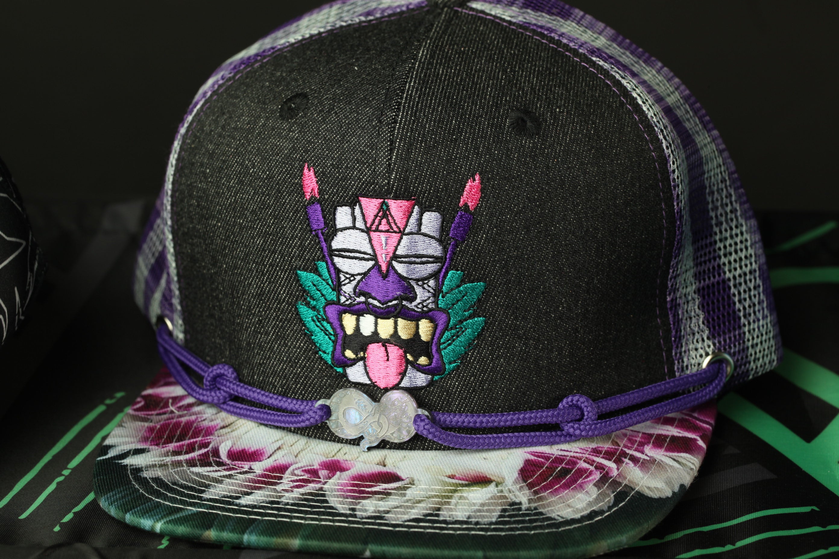 a black baseball cap with a colorful, embroidered design on the front.