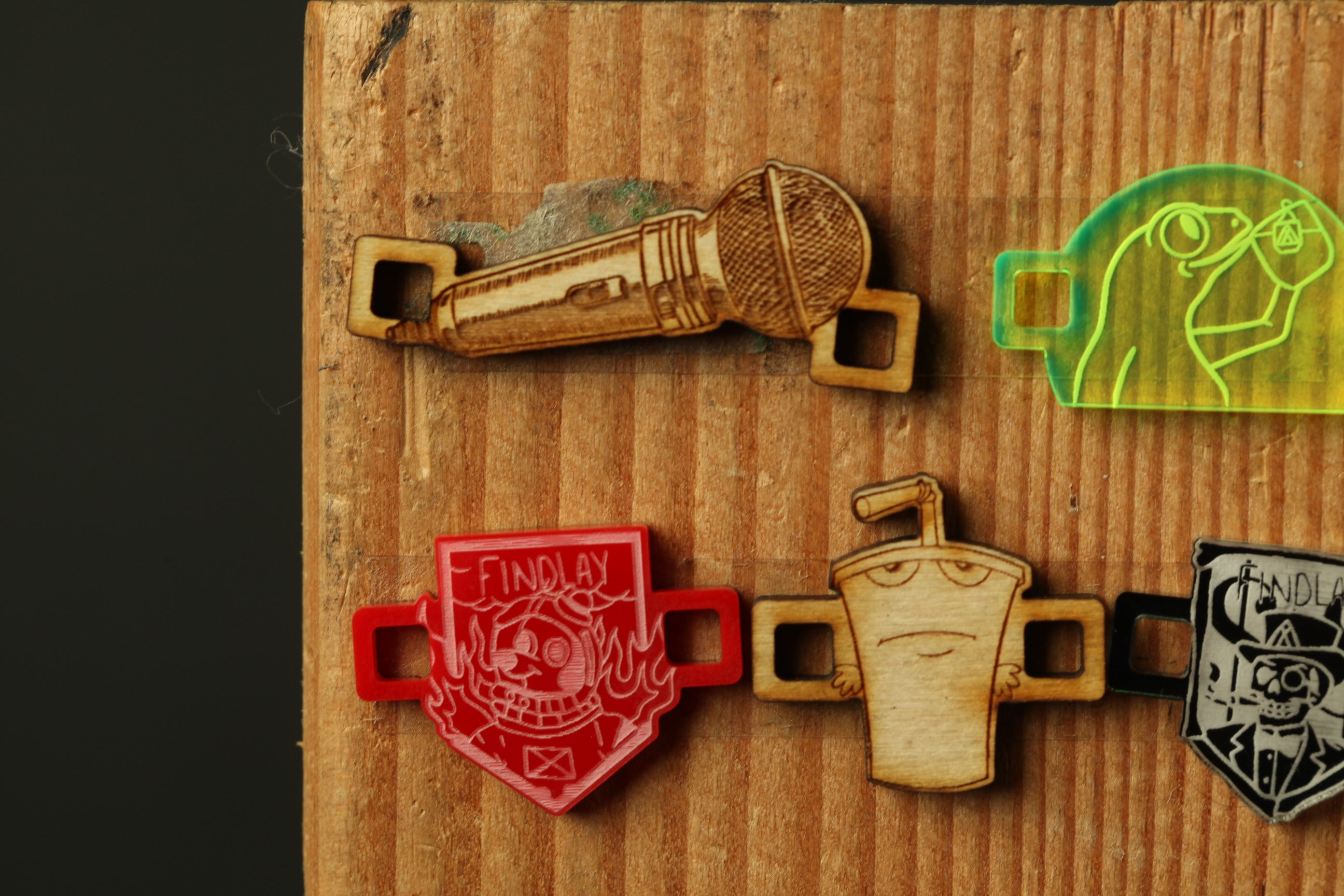 a wooden surface with various objects attached to it, including a microphone, a cup, and a character.