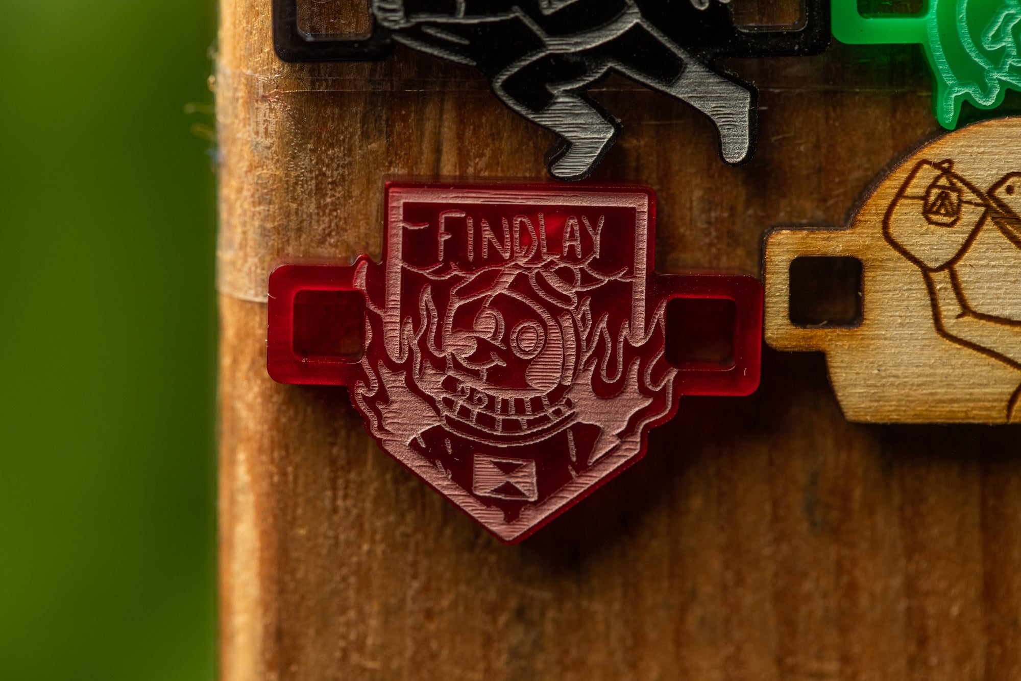 a red badge with a skull and crossbones design, attached to a wooden surface.
