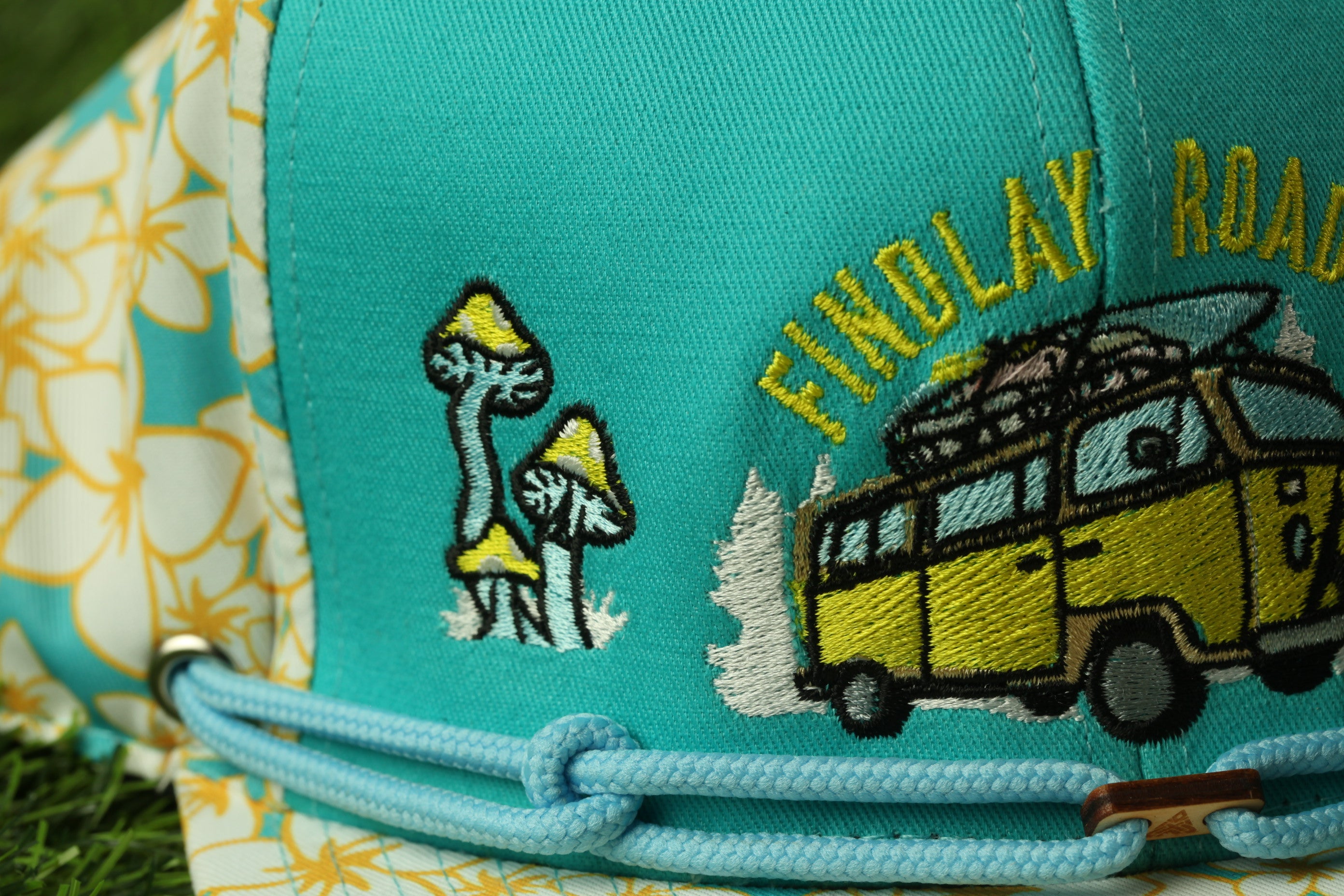 a close-up of a colorful baseball cap with a floral pattern and a yellow van embroidered on it.