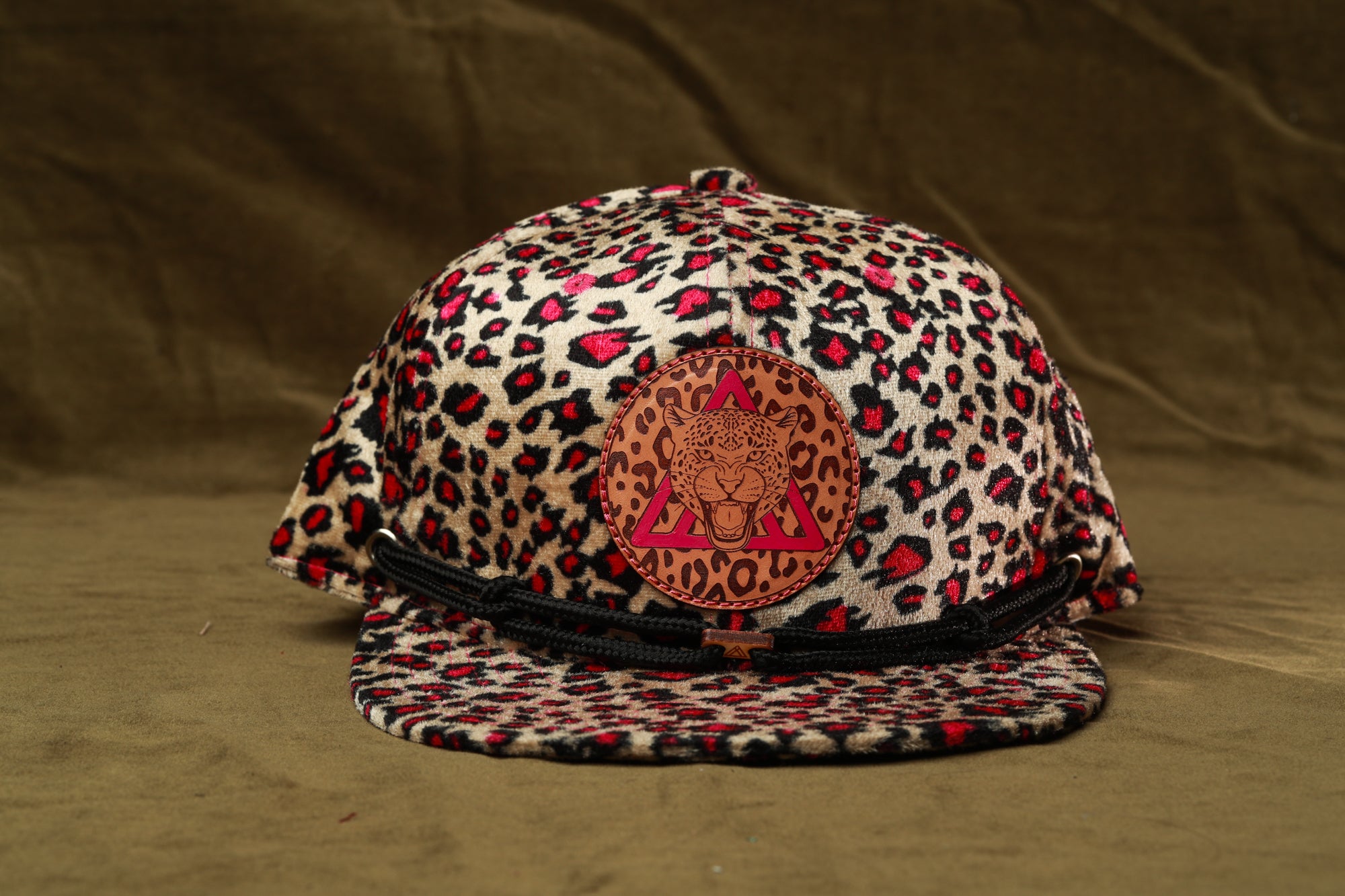 A leopard print baseball cap with a red and black logo on the front.
