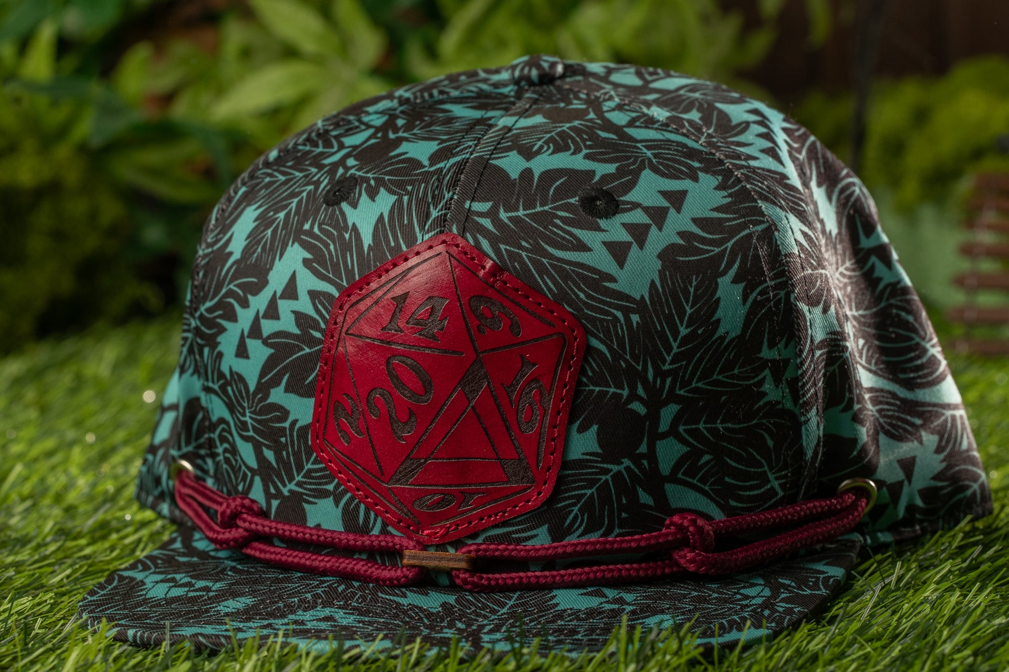A close-up image of a baseball cap with a patterned design and a red hexagonal patch on the front.