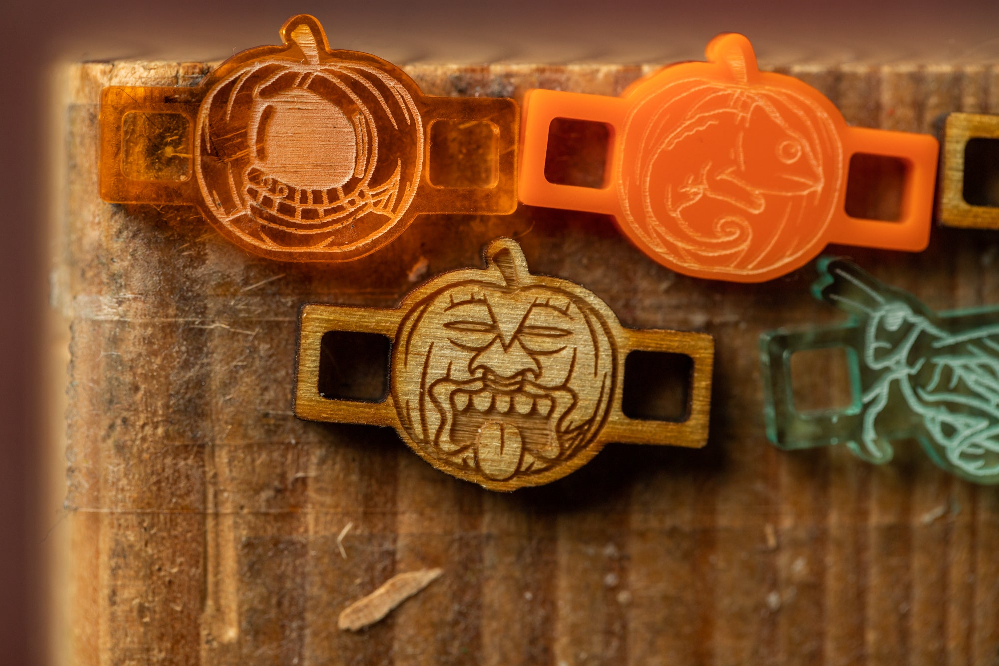 Halloween-themed plastic charms, including a pumpkin, a chameleon, and a ghost, displayed on a wooden surface.