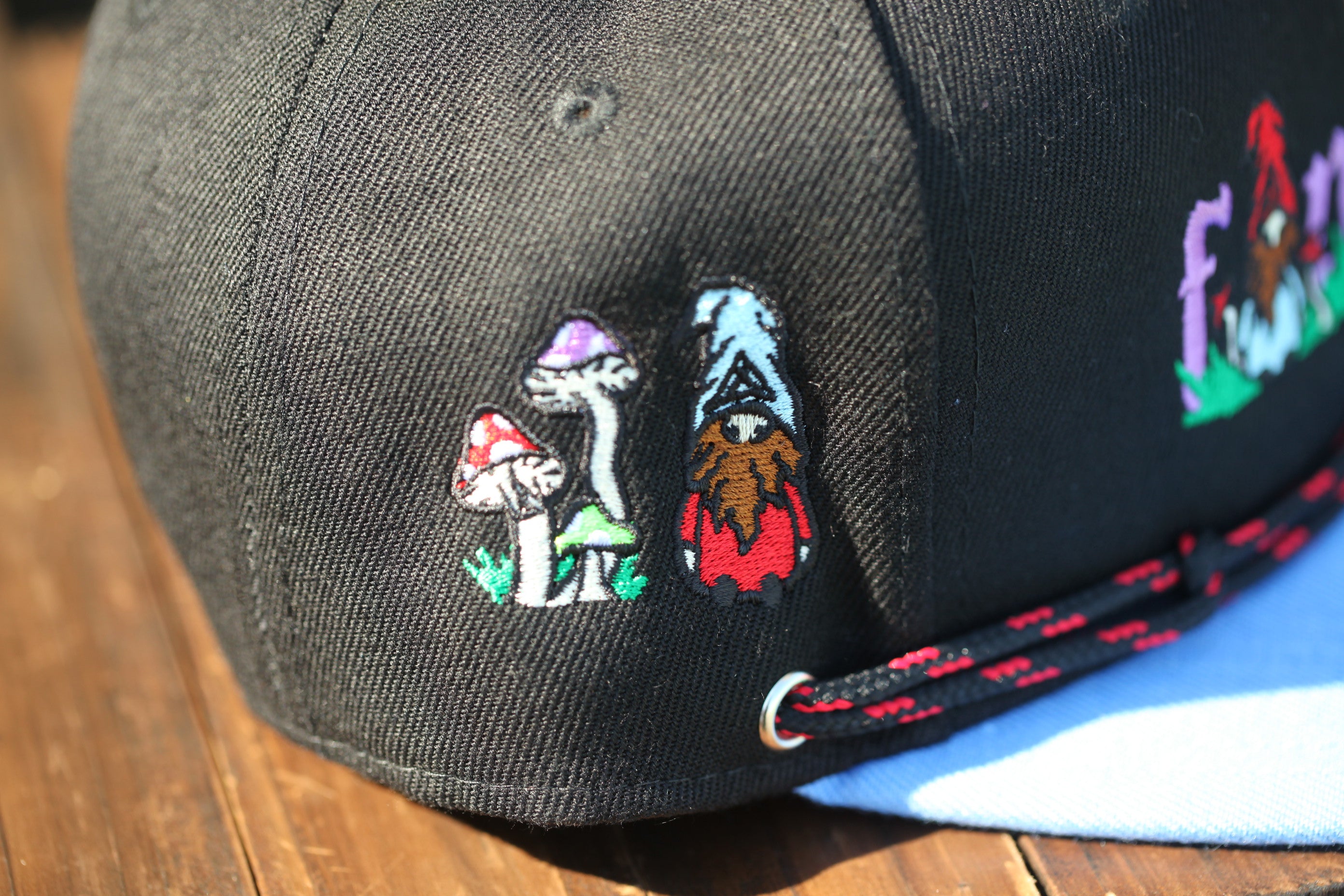 a close-up view of a black baseball cap with colorful embroidered designs on the front.