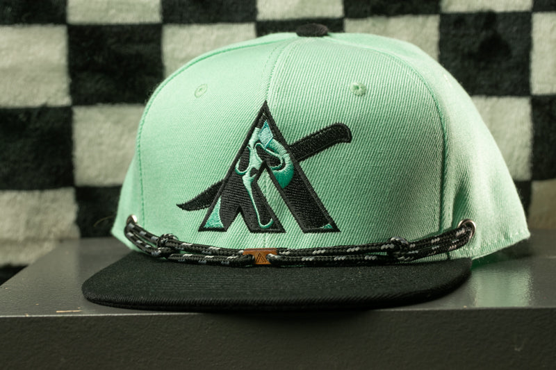 A mint green baseball cap with a black brim and a black and white checkered pattern on the background.