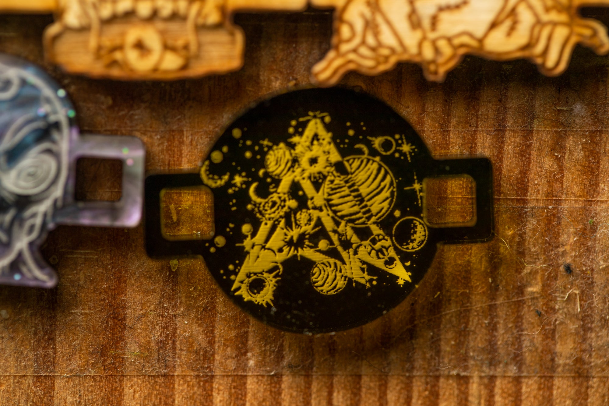 a black circular object with a yellow and black design, including a triangle, planets, and other celestial elements, mounted on a wooden surface.