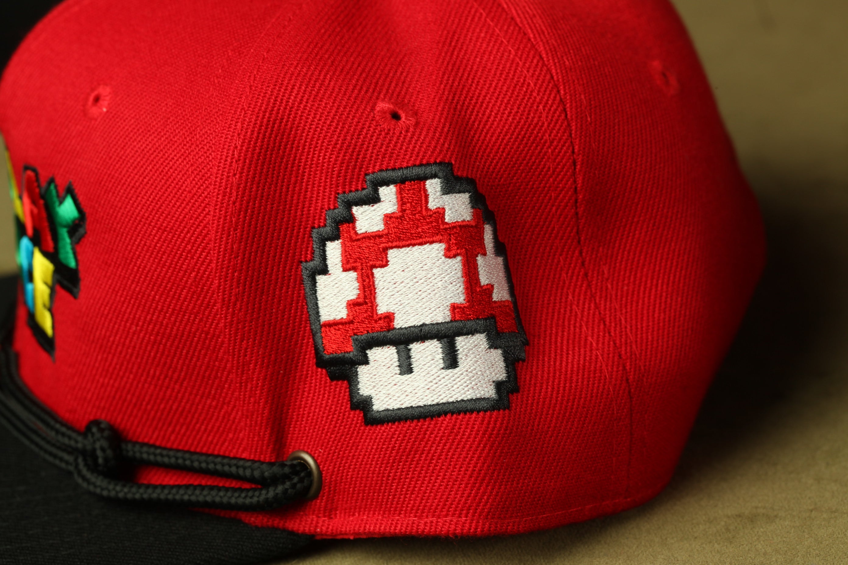 A red baseball cap with a pixelated mushroom design on the front.
