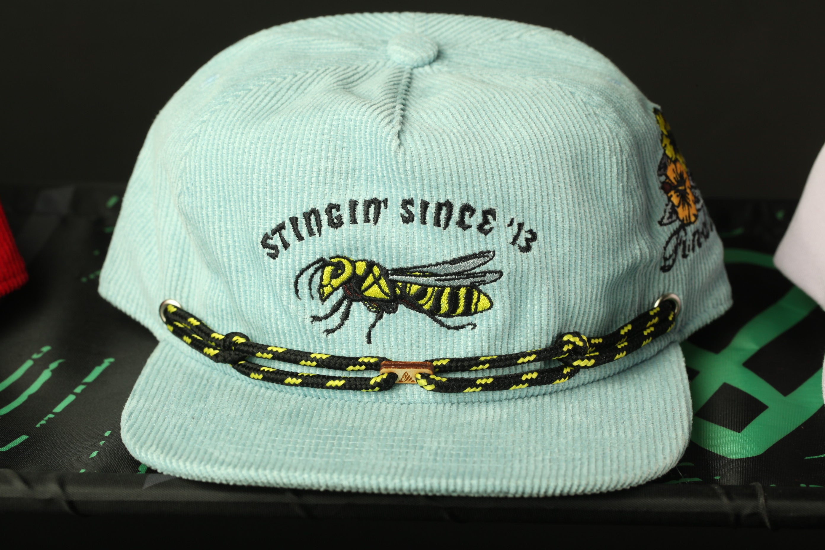 A light blue baseball cap with a black and yellow bee embroidered on it, featuring the text "Stinger since '13" on the front.