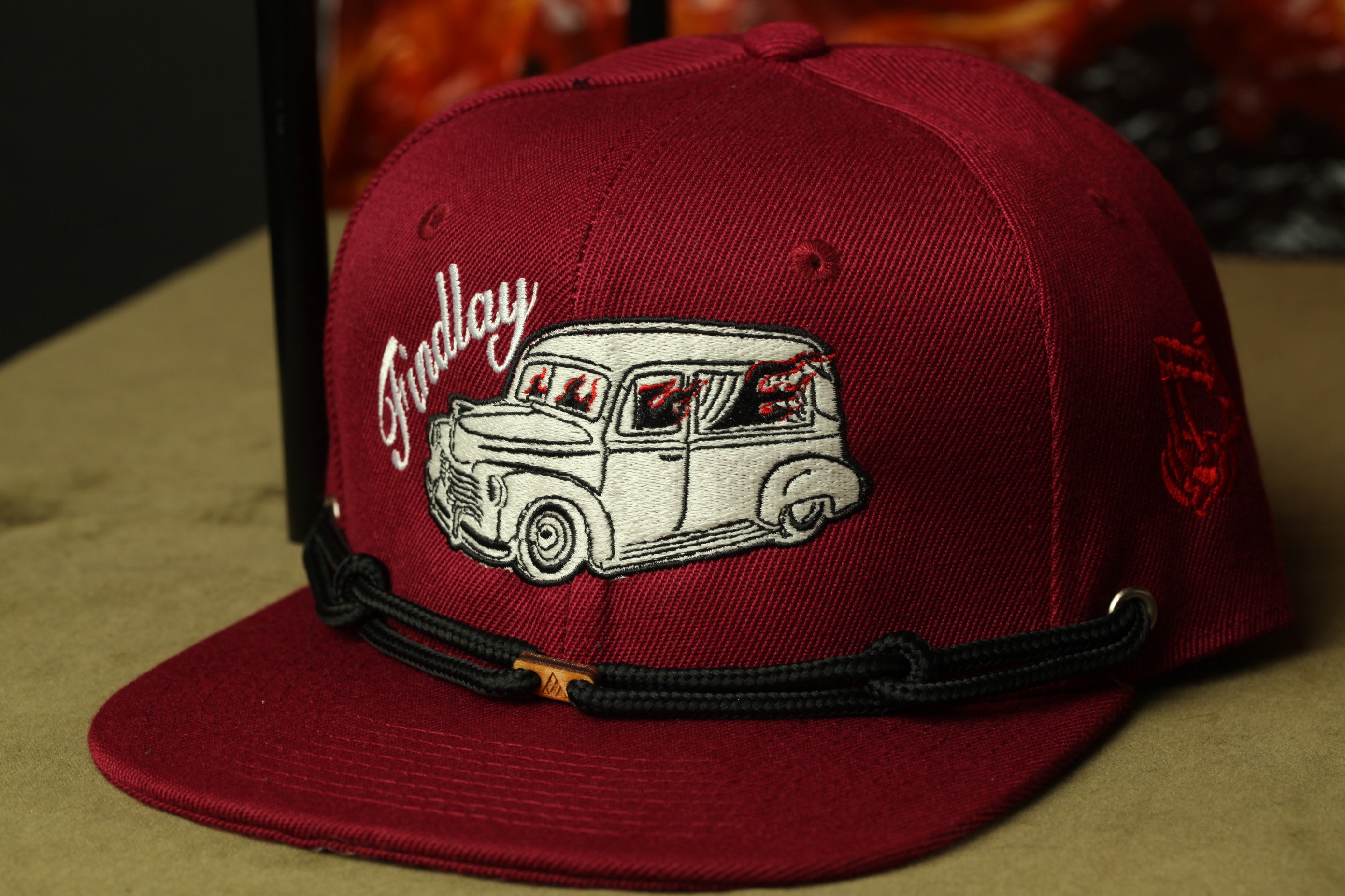 A maroon baseball cap with a vintage car embroidered on it, featuring the word "Ford" on the front.