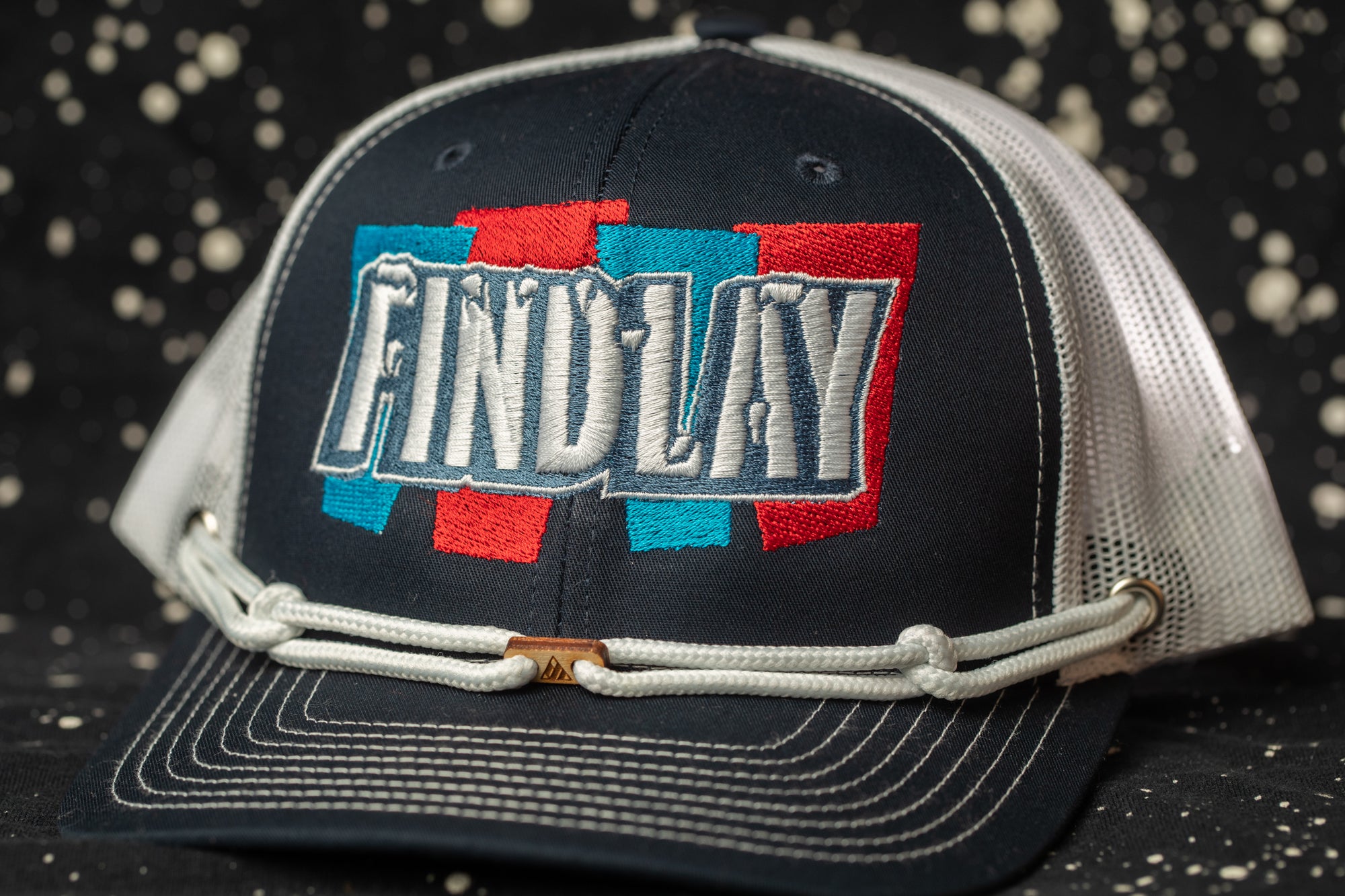 A black baseball cap with a white mesh panel and a red, blue, and white embroidered logo on the front.