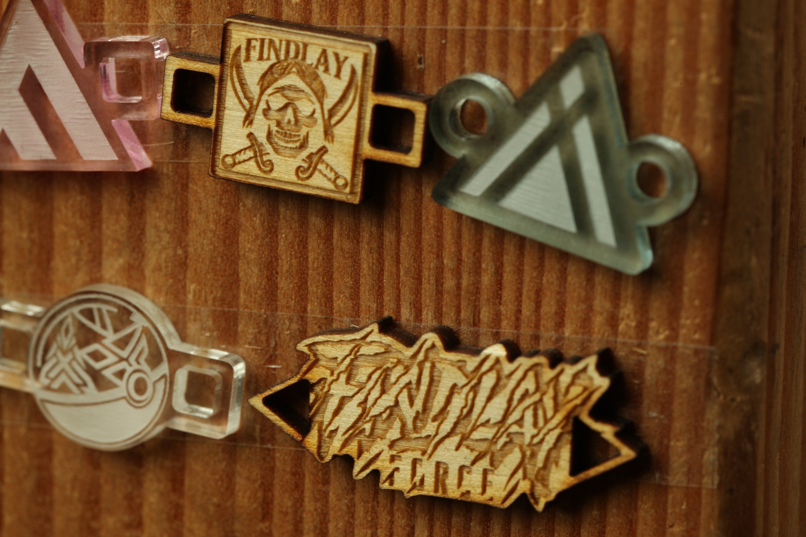 a wooden surface with various engraved and printed objects, including a wooden sign with the word "FIND LAY" and a metal triangle.