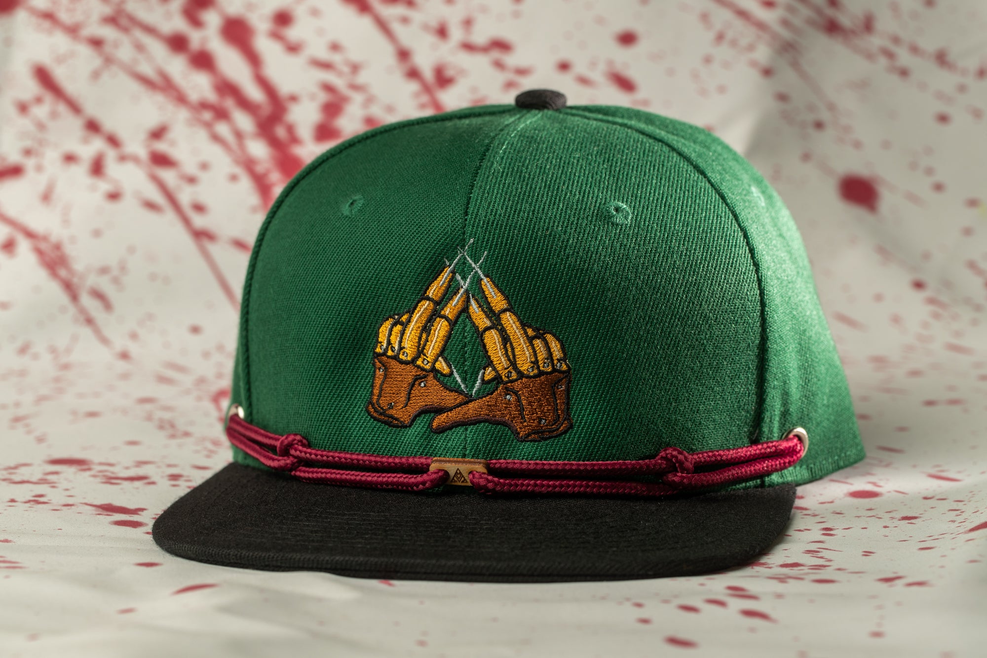 A green baseball cap with a graphic design on it, featuring a pair of crossed fingers.