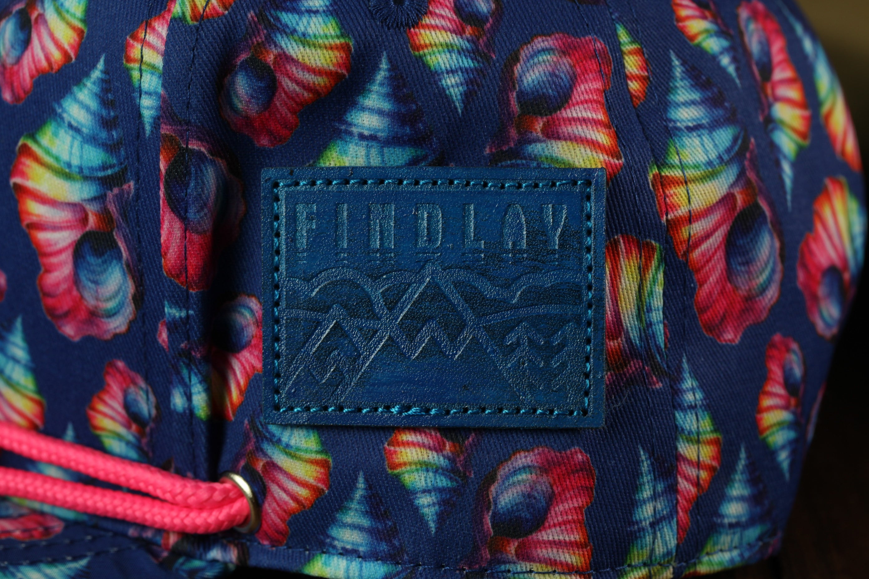 A close-up view of a colorful, patterned fabric with a blue patch featuring the word "FINDlay" printed on it.