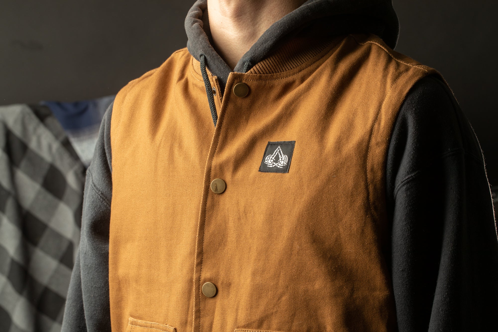A close-up of a person wearing a yellow vest with a black logo on the chest.
