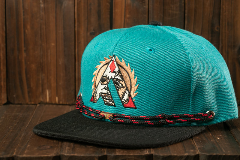 A turquoise baseball cap with a black brim and a red and black braided strap, featuring an embroidered logo on the front.