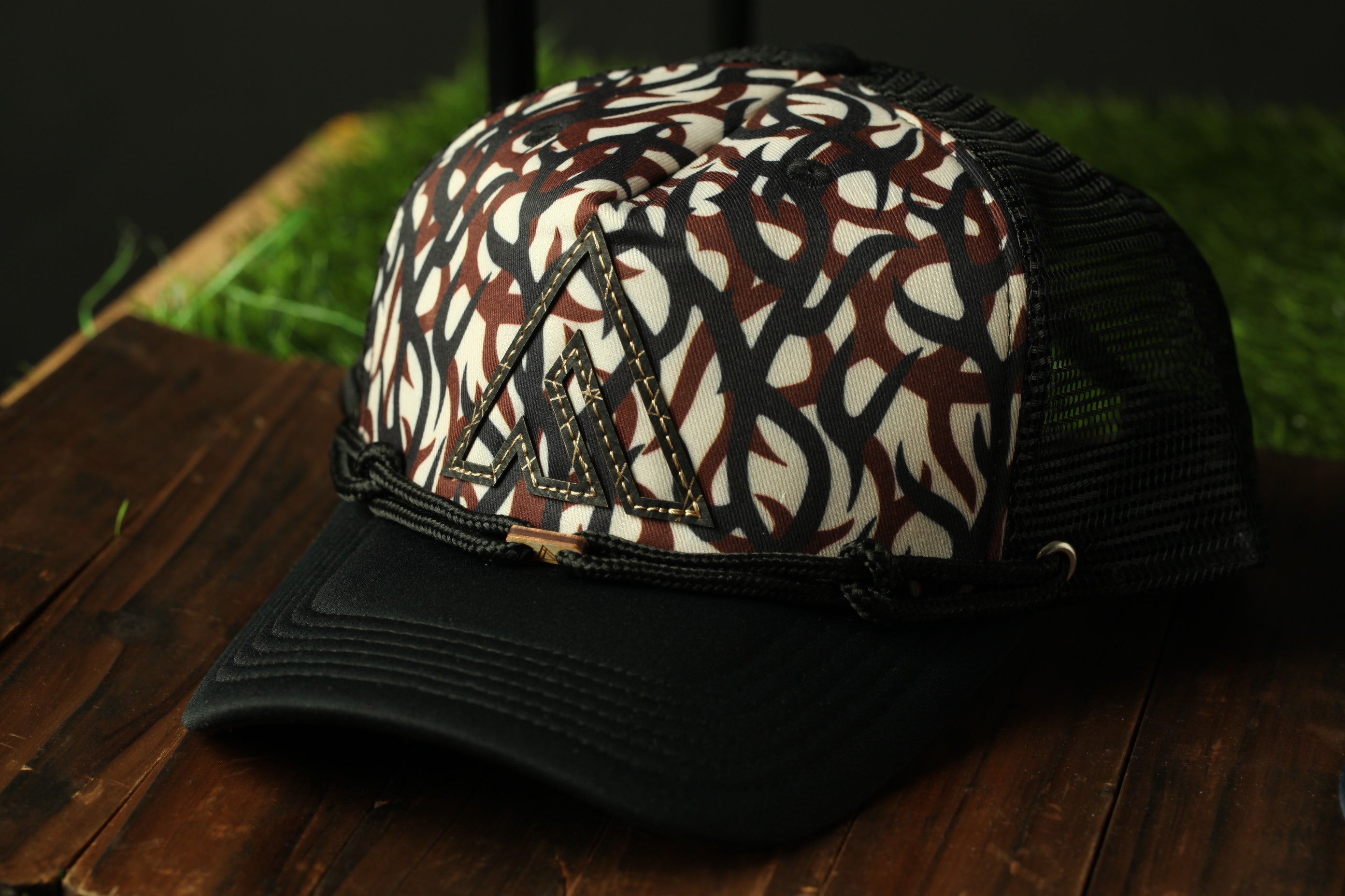 A black baseball cap with a patterned design sits on a wooden surface.