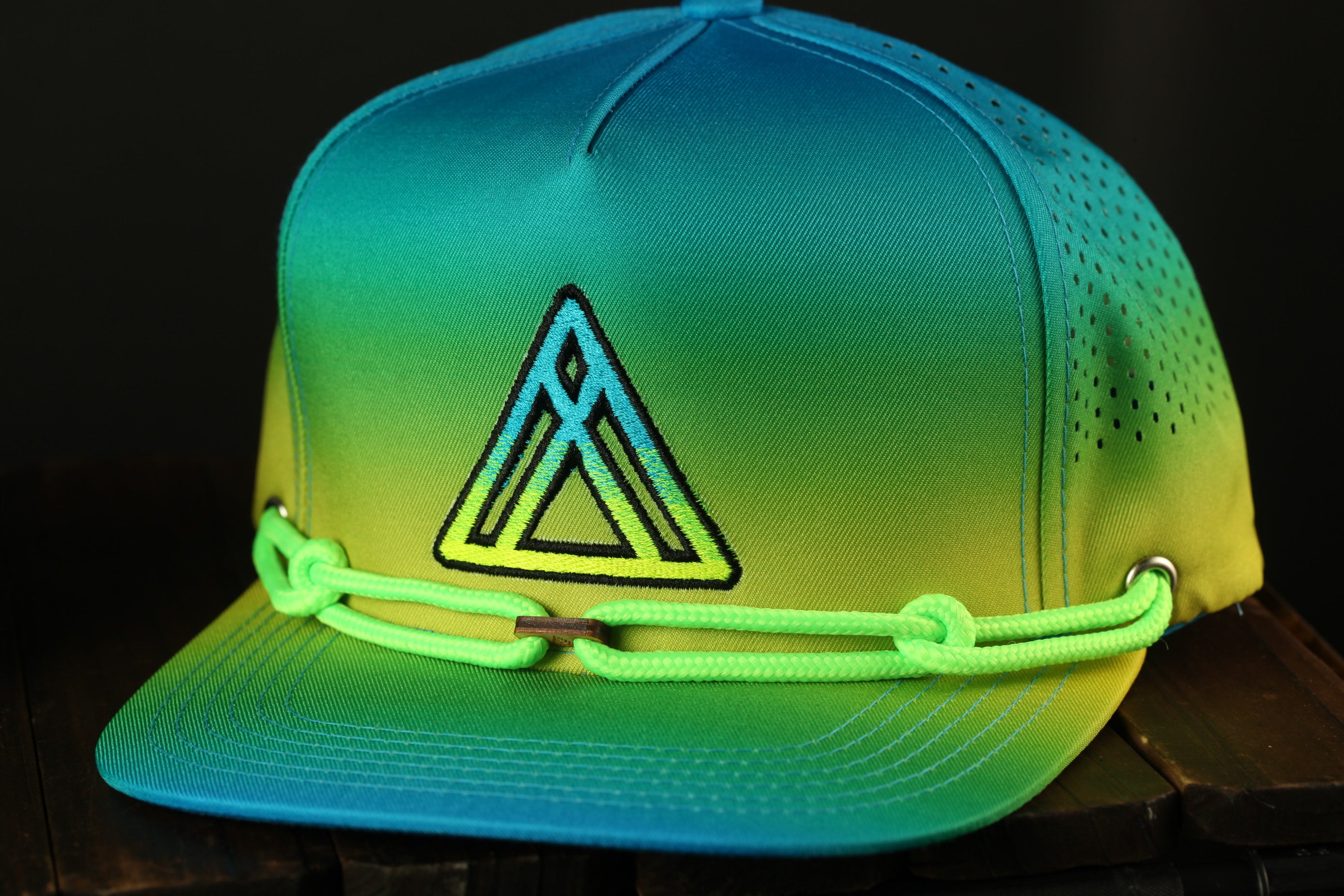 A colorful, gradient-colored baseball cap with a geometric pattern and neon green straps.