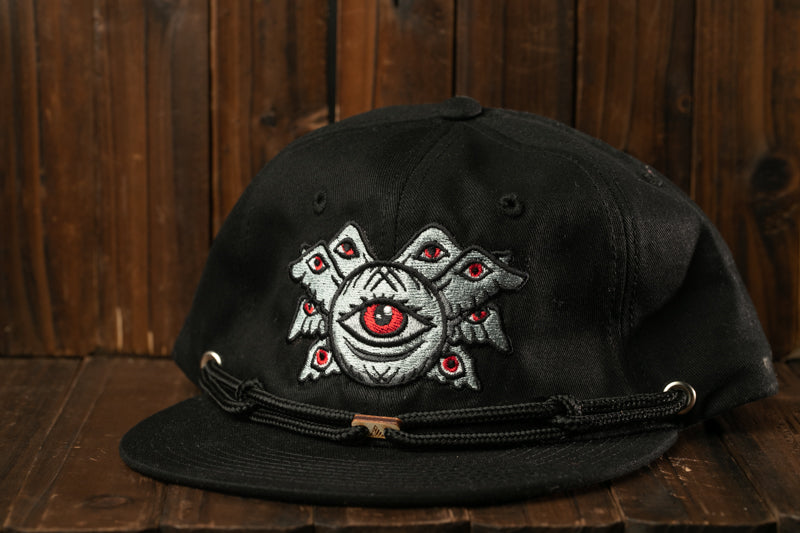 A black baseball cap with a unique embroidered design on the front, featuring a central eye surrounded by multiple smaller eyes.