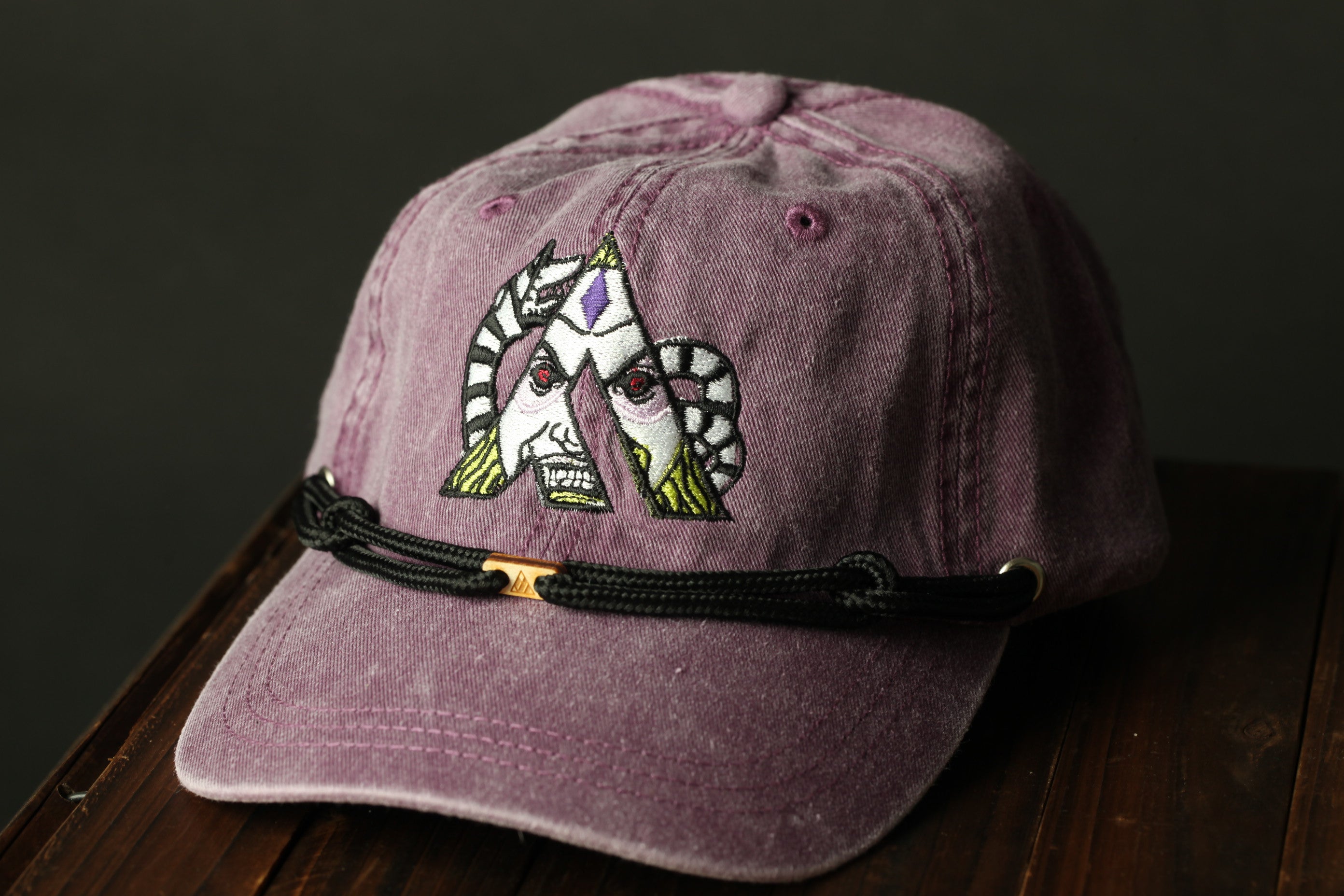 A purple baseball cap with a unique embroidered design on the front.
