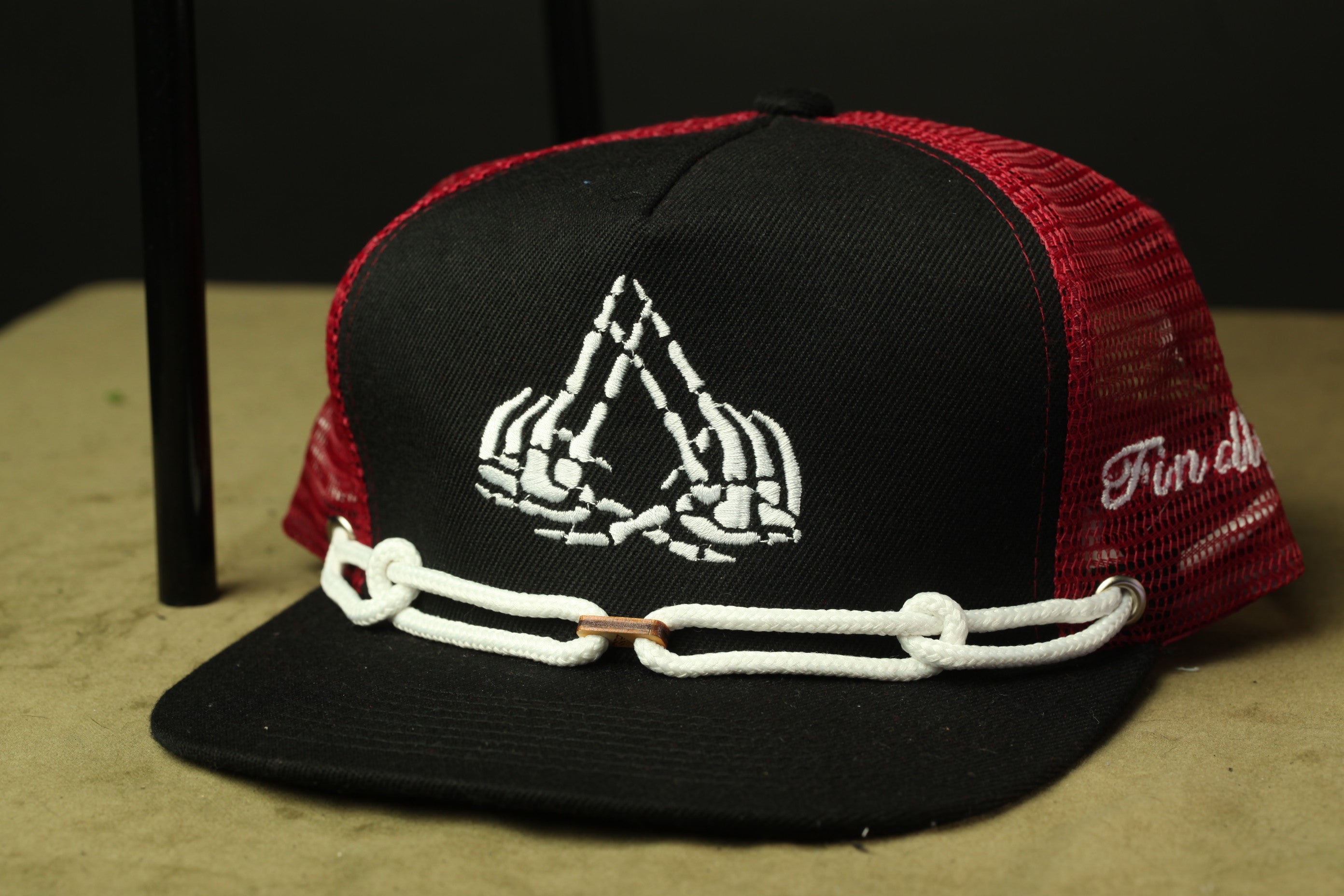 A black and red baseball cap with a white skull design on the front.