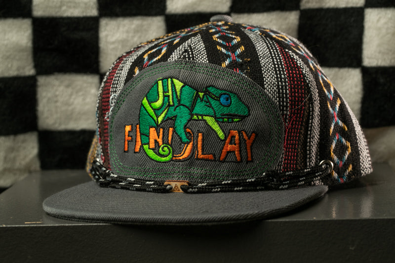 A colorful, patterned baseball cap with a graphic of a chameleon on the front.