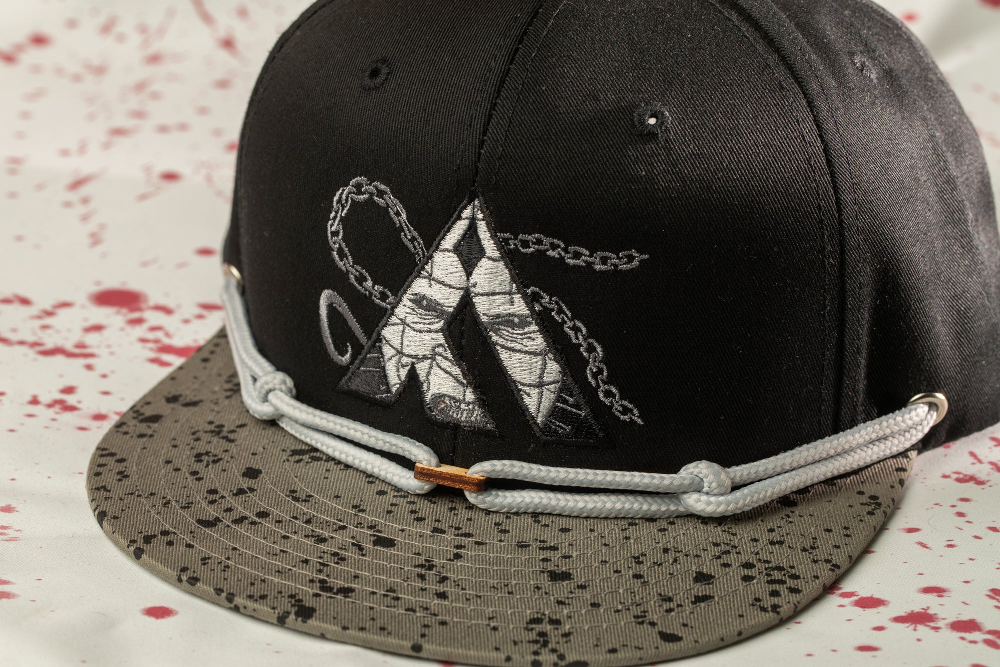 A black baseball cap with a unique embroidered design on the front.