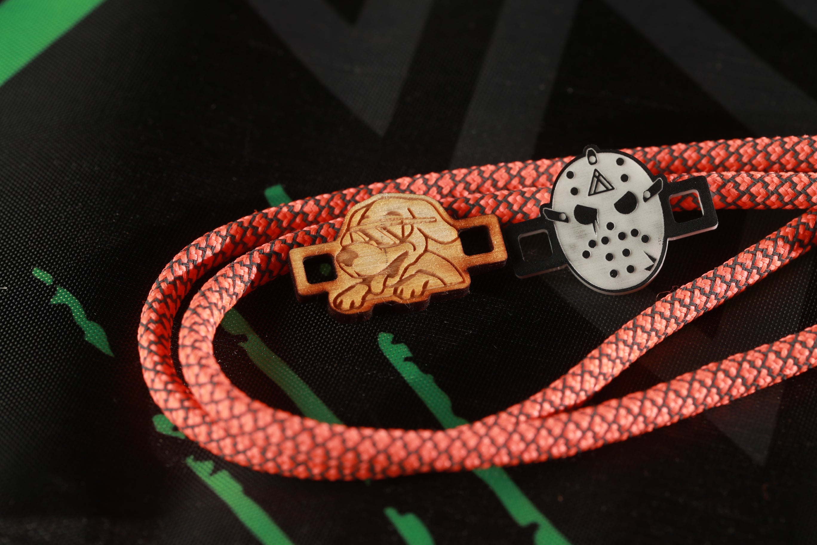 a pair of wooden and plastic shoe laces with a Halloween theme, including a wooden lion and a plastic mask with a triangular design.