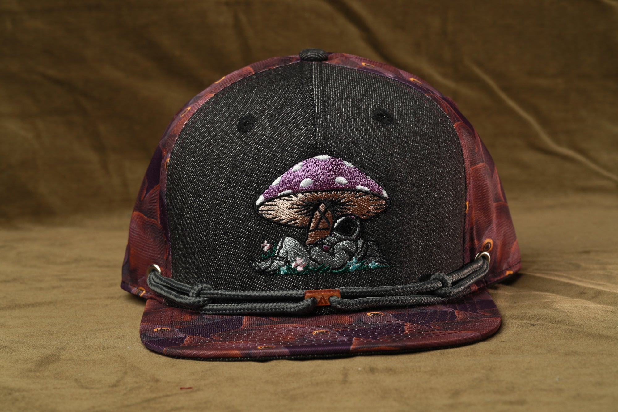 A black baseball cap with a purple mushroom design on the front.