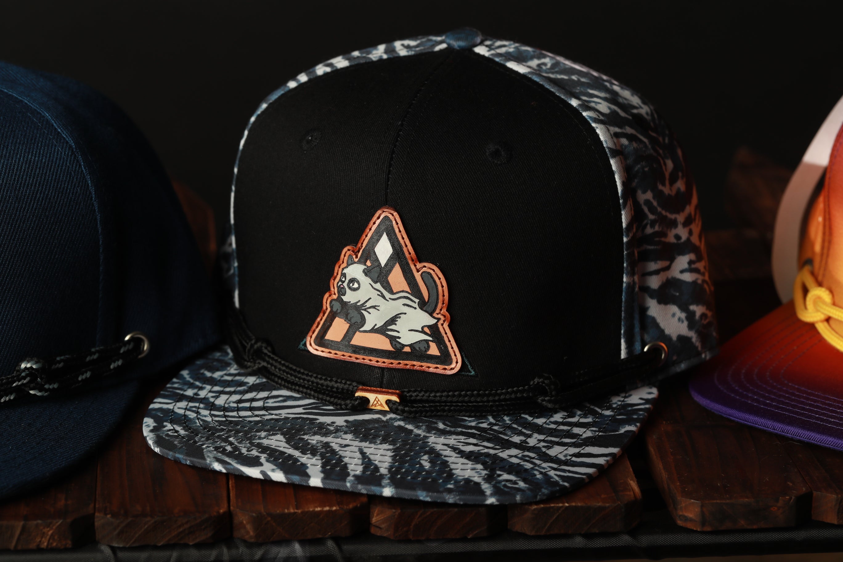 A close-up view of a black and white patterned baseball cap with a graphic patch on the front.