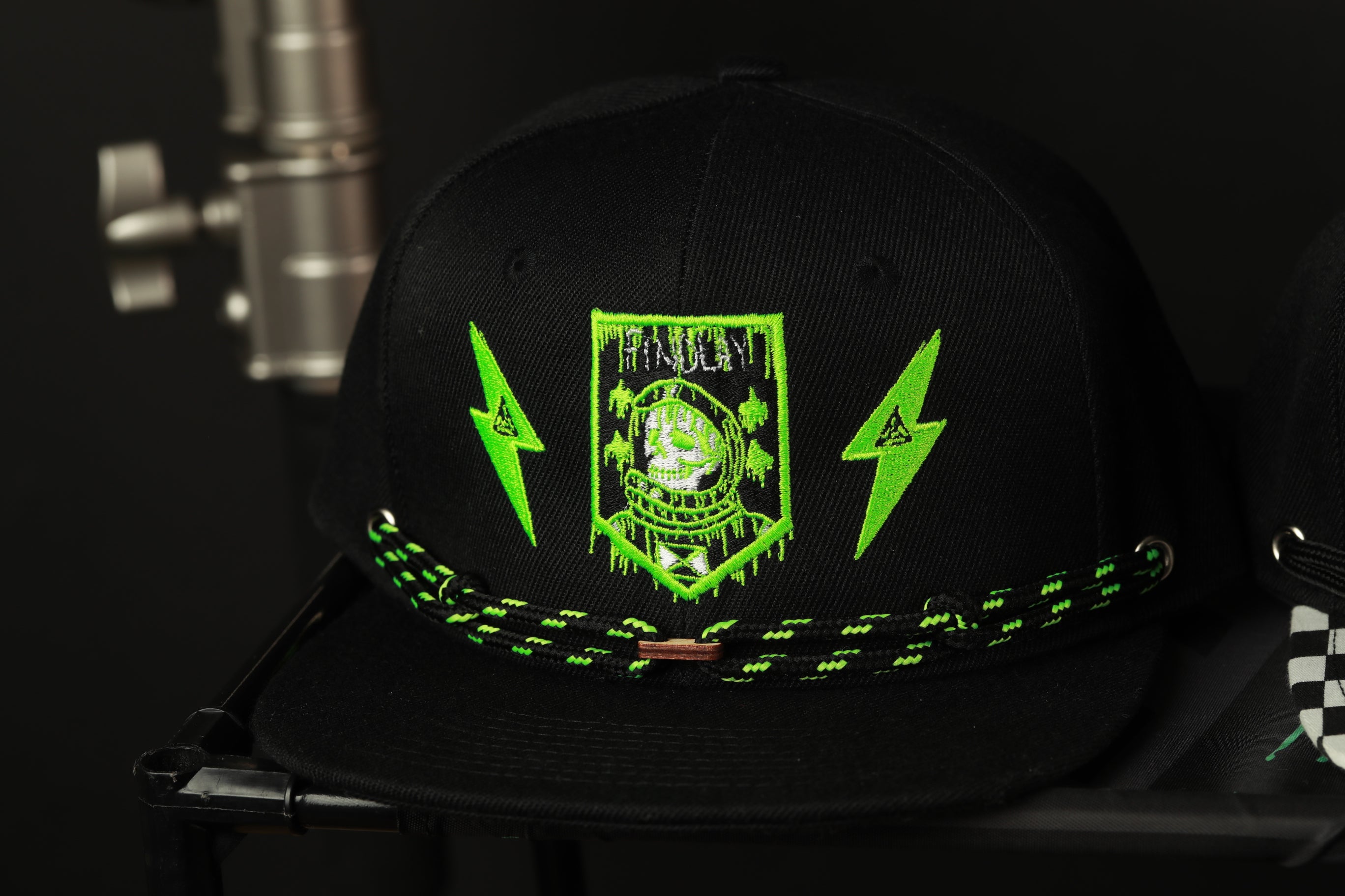 A black baseball cap with a green and black design featuring a skull and lightning bolts.