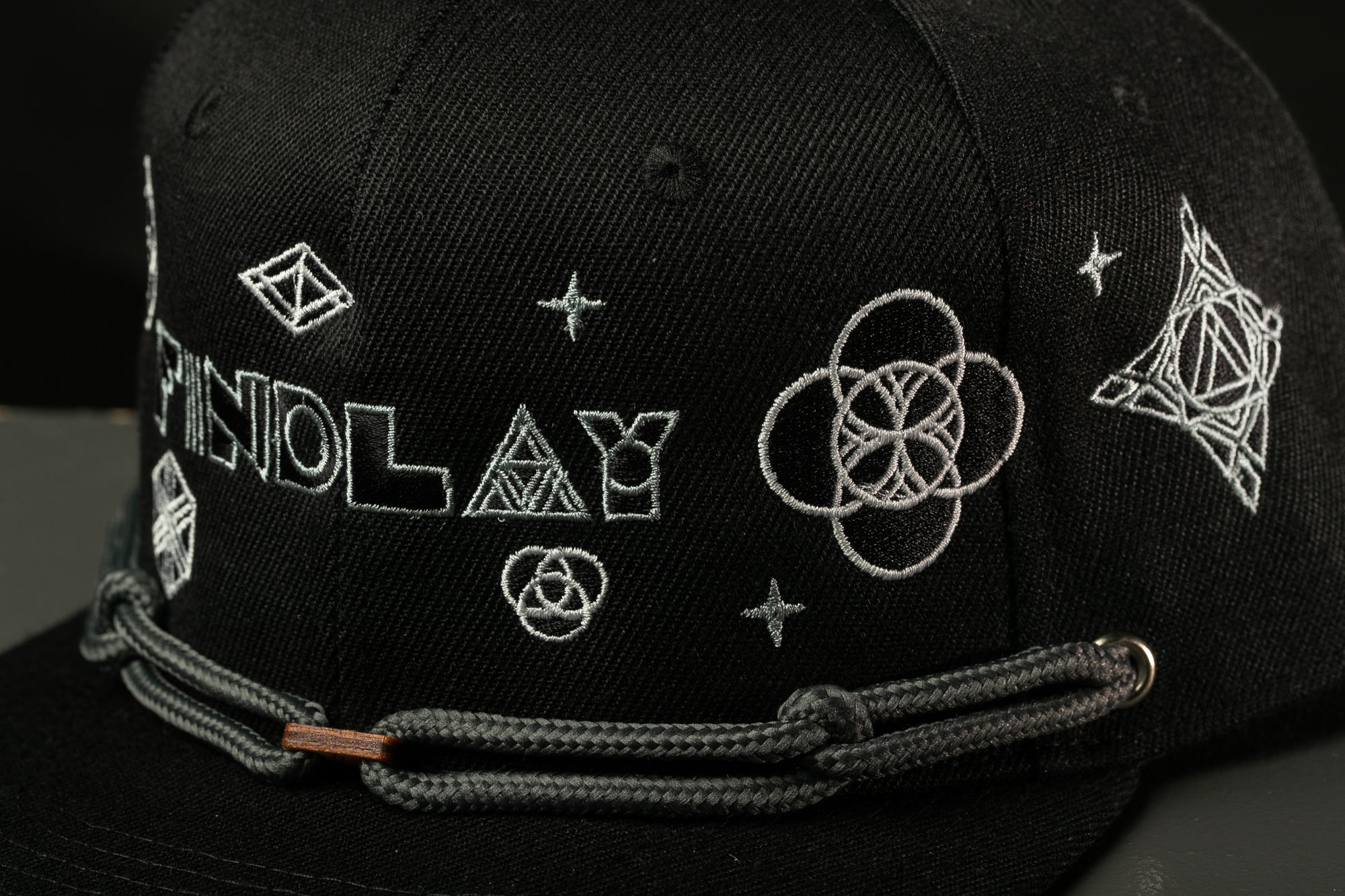 A close-up view of a black baseball cap with various embroidered designs and text on it.
