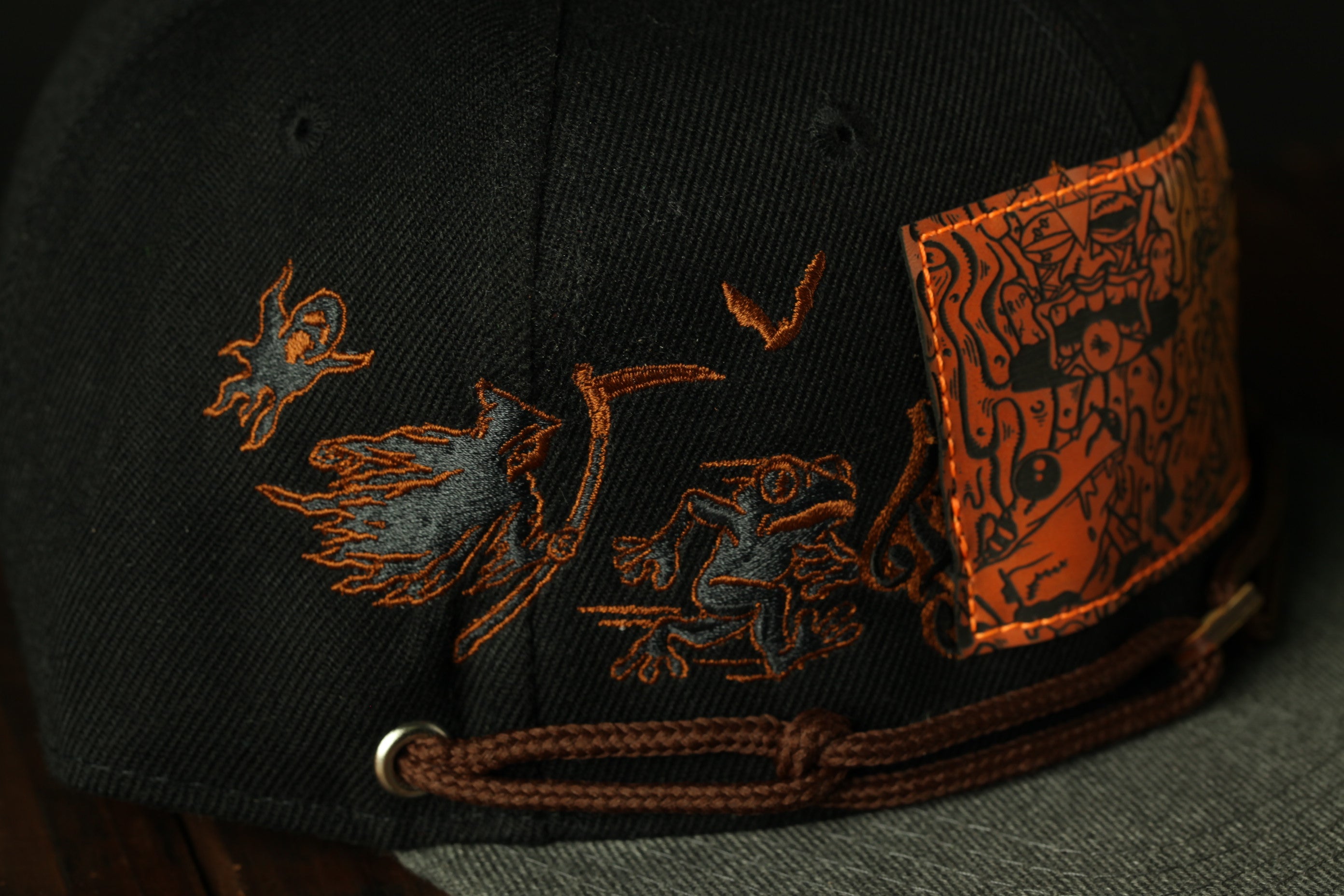 a close-up view of a black baseball cap with an orange and black design on the front.