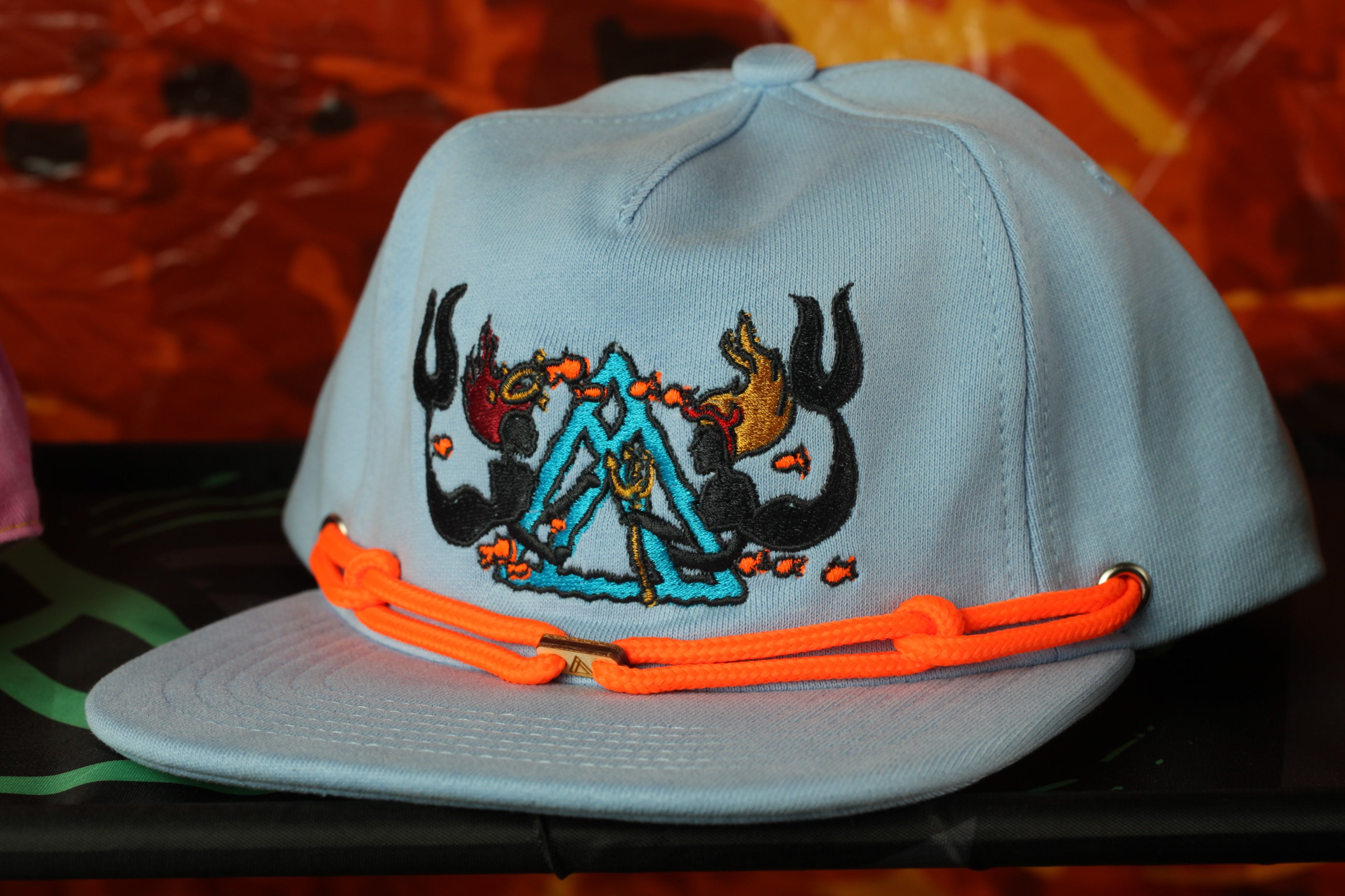 A light blue baseball cap with a colorful, embroidered design on the front.