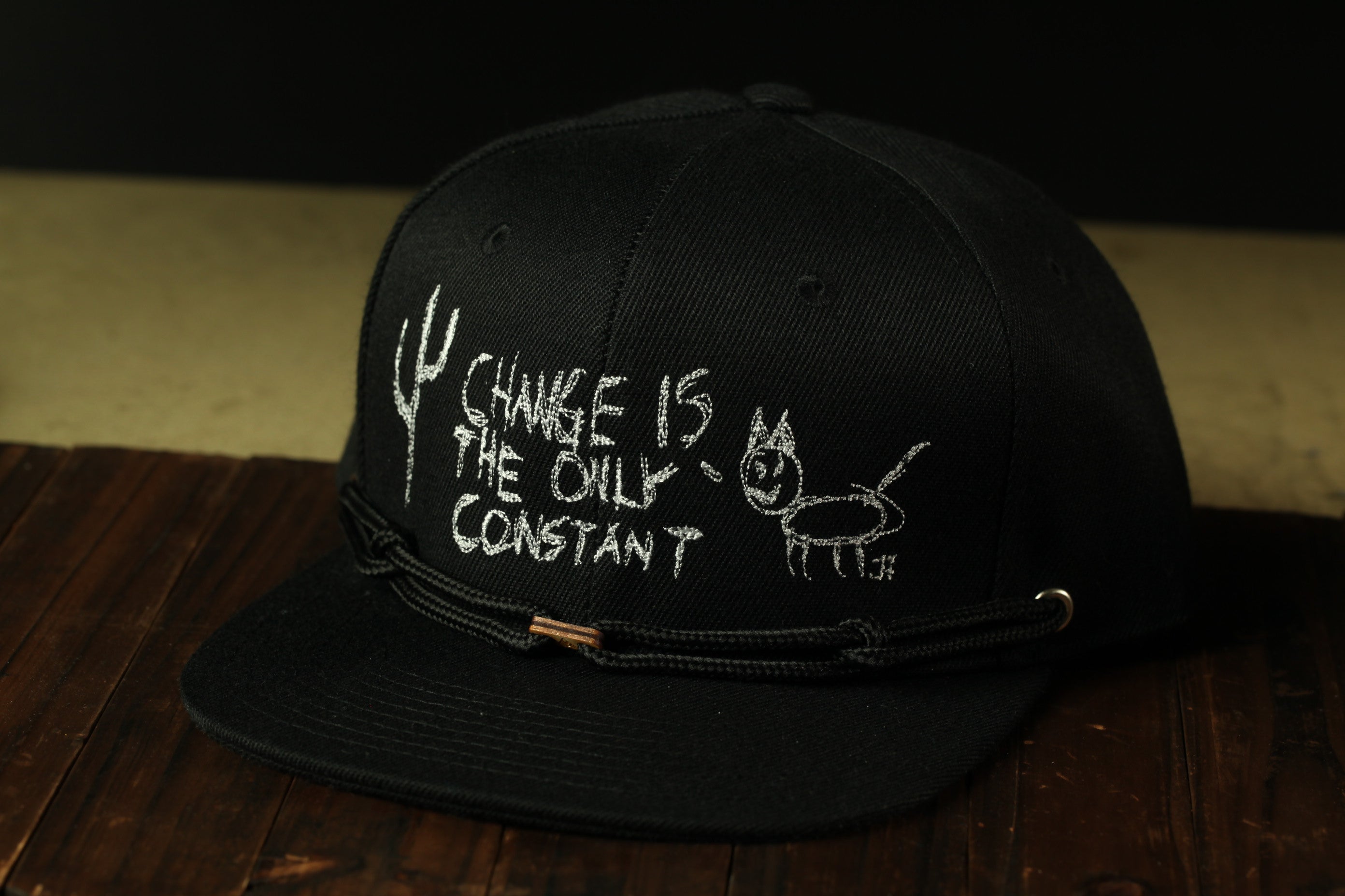 A black baseball cap with white text and drawings on it.