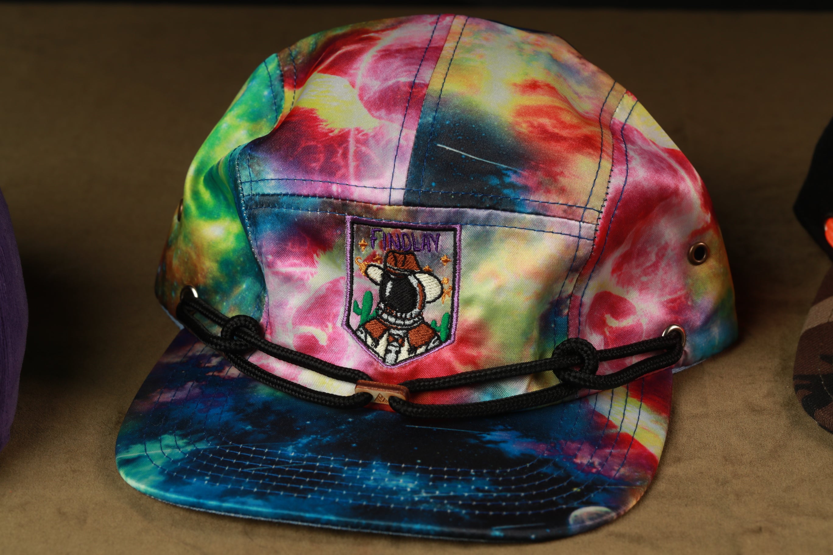 A colorful tie-dye baseball cap with a patch on the front.